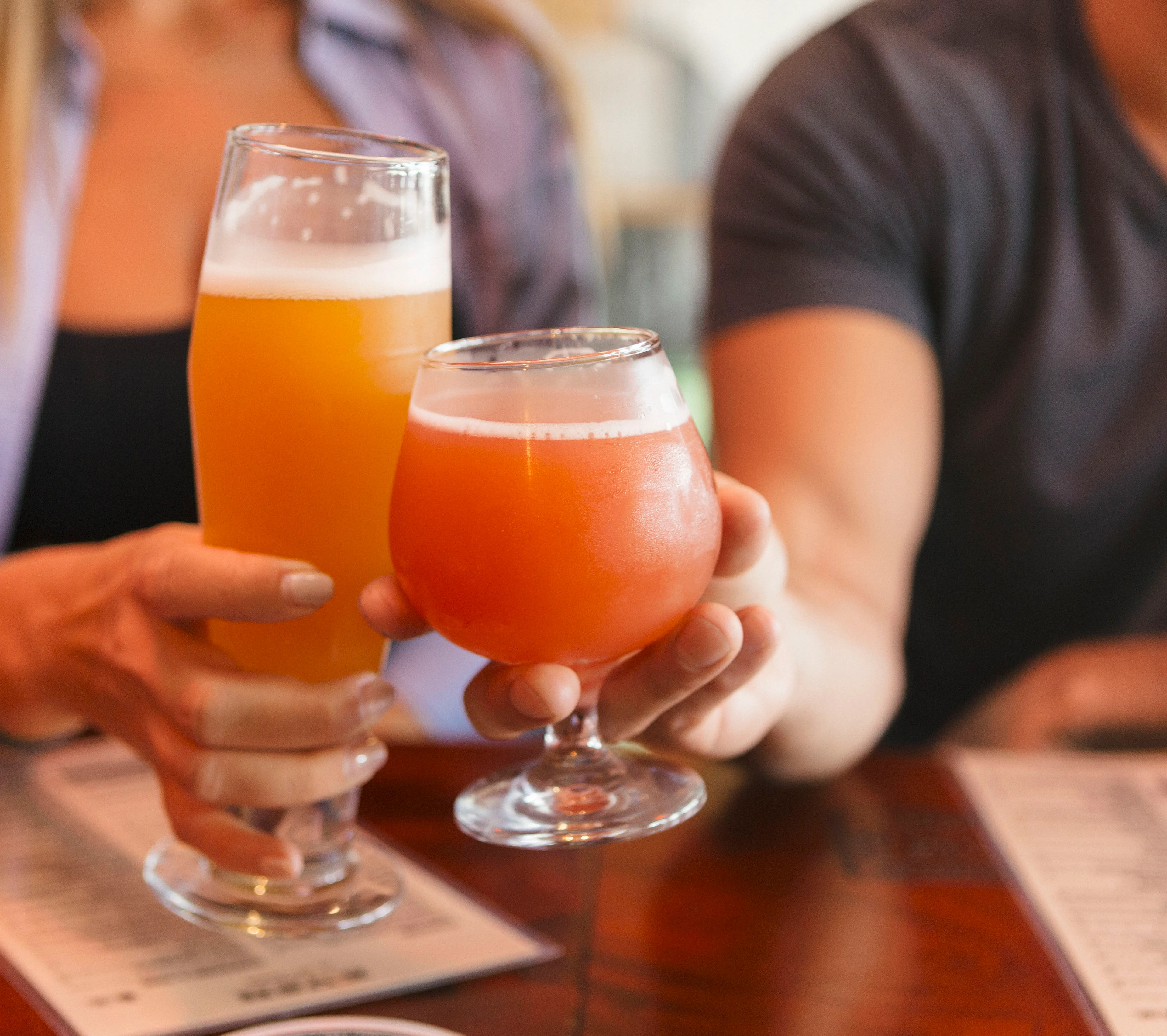 Two craft beers clinking in a cozy bar setting
