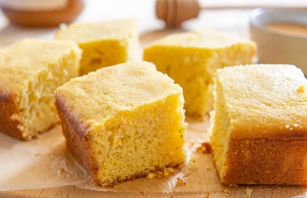 Freshly baked cornbread squares arranged on a wooden surface, showcasing their golden brown crust and soft interior.