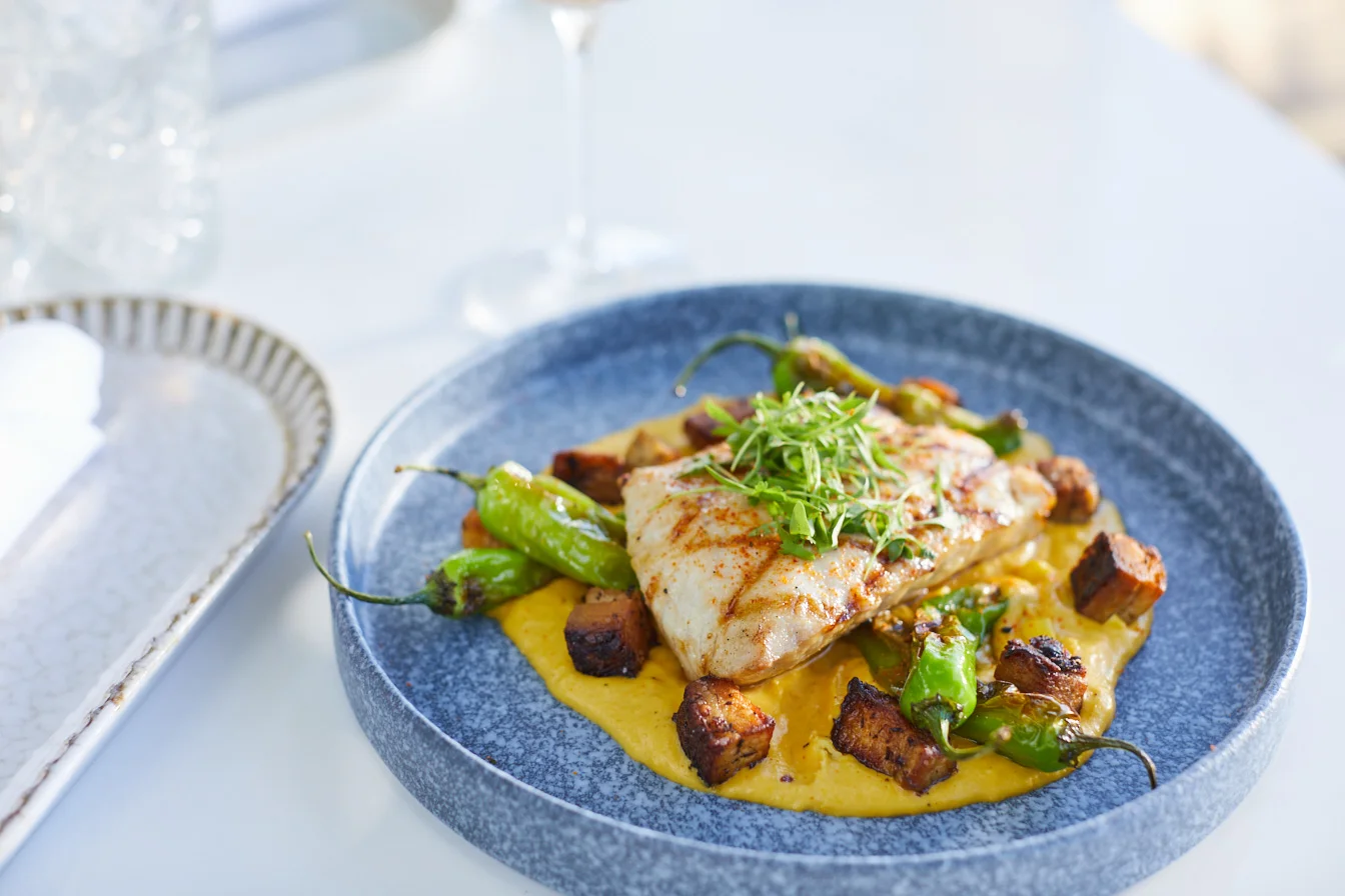 Grilled fish with creamy polenta and shishito peppers