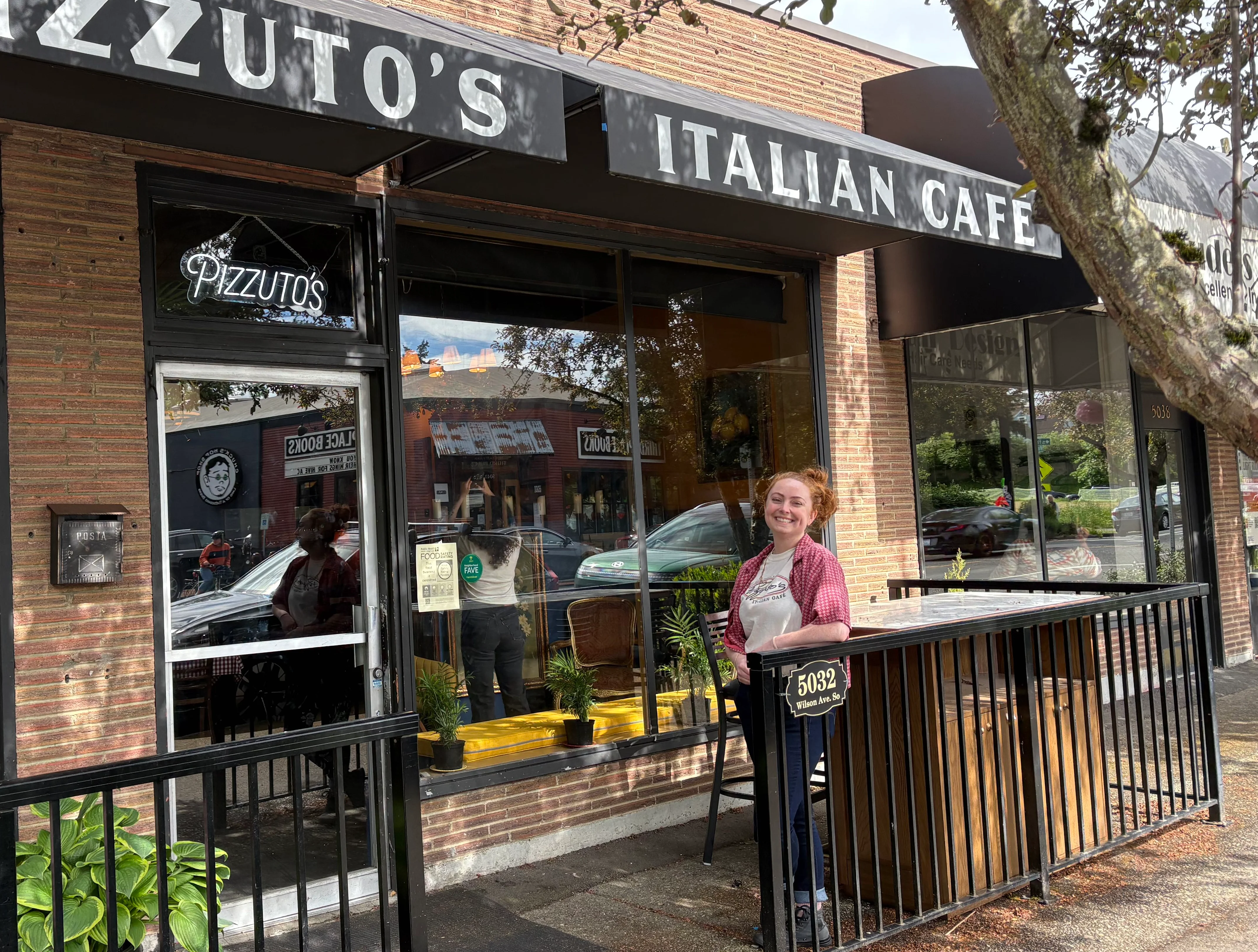 Exterior of Pizzuto's Italian Cafe with a smiling staff member.