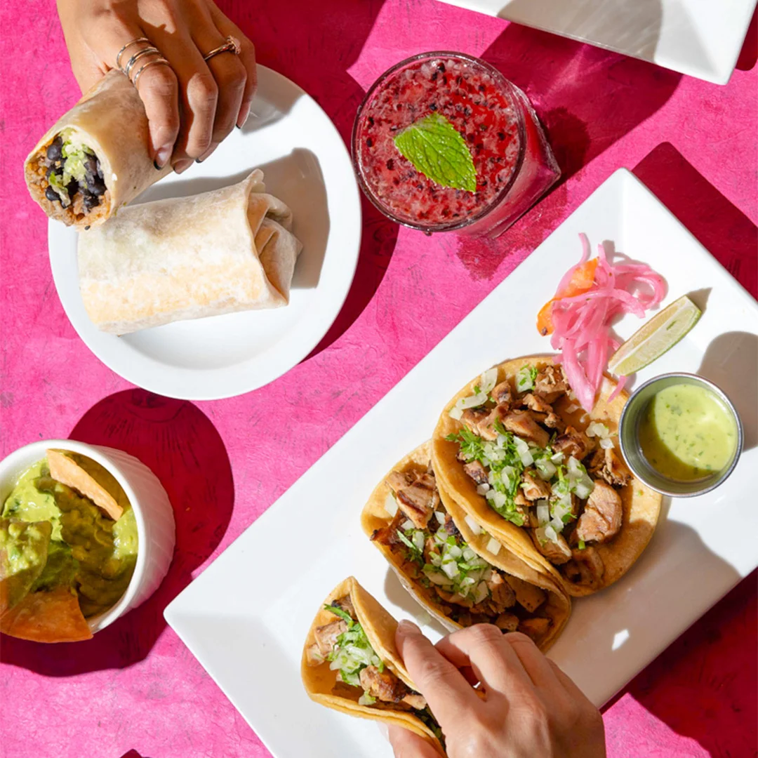 Hands holding tacos at Friducha, a Mexican restaurant in Brooklyn, NY.