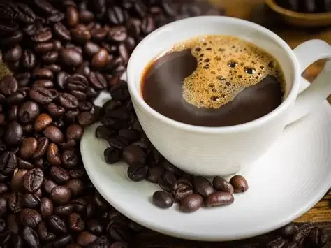 Freshly brewed coffee in a white cup with roasted beans