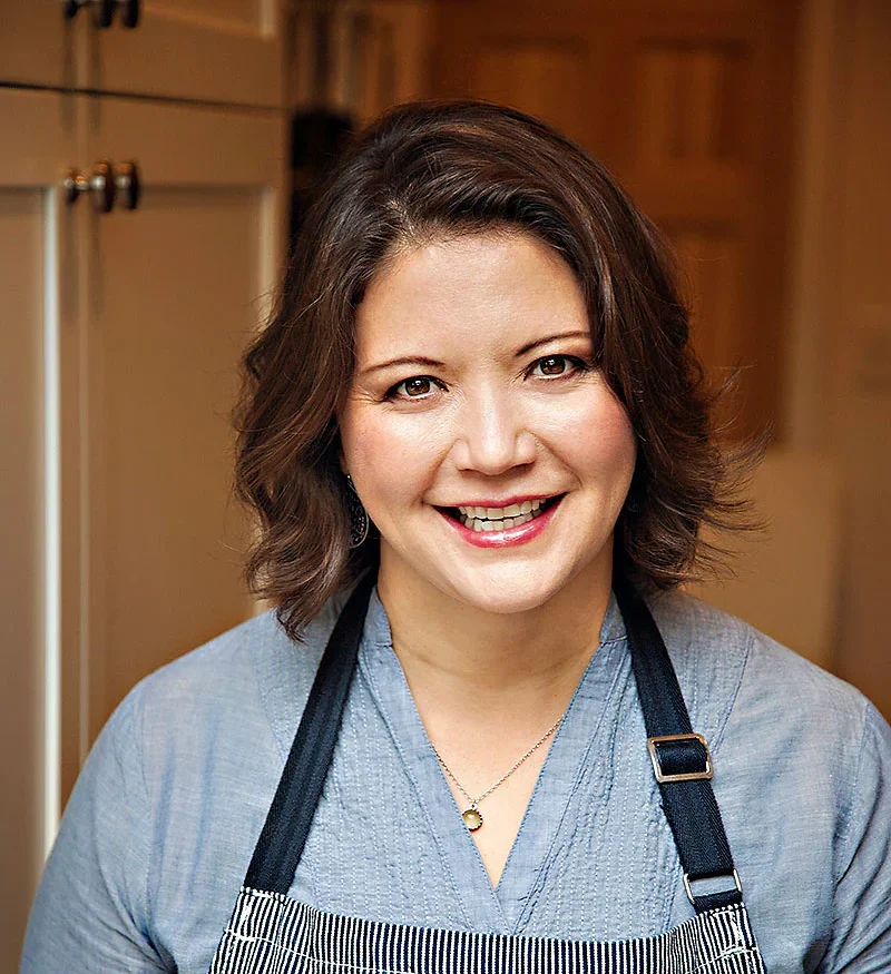 Chef smiling in a kitchen wearing an apron