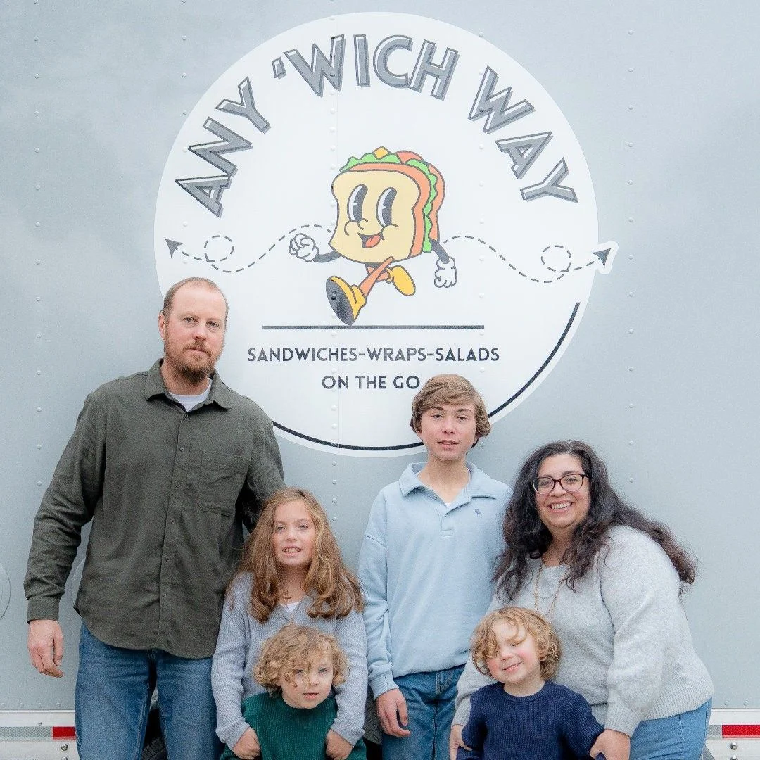 Family in front of food truck named Any 'Wich Way