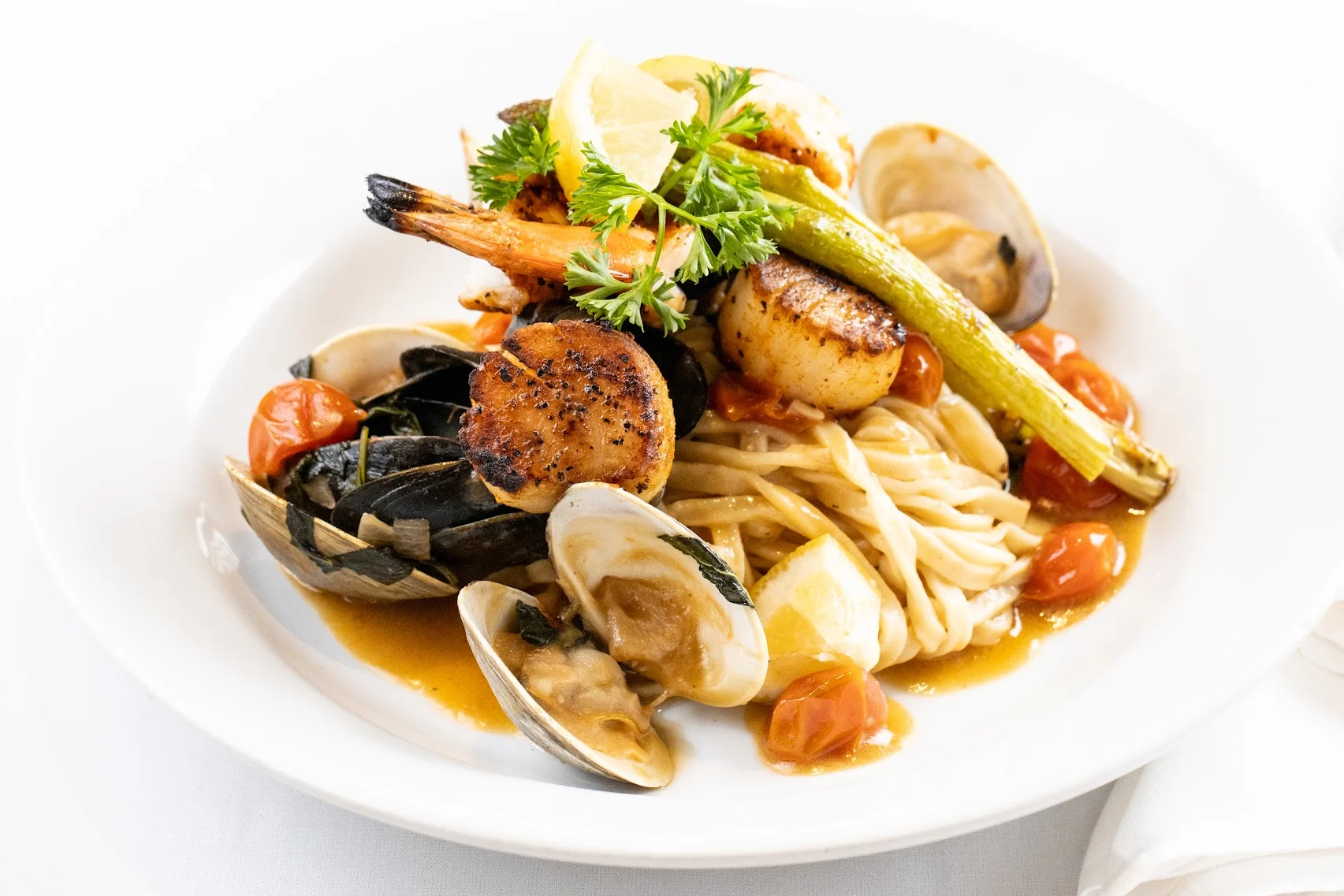 Seafood dish with shrimp and scallops on top mixed in a red clam sauce