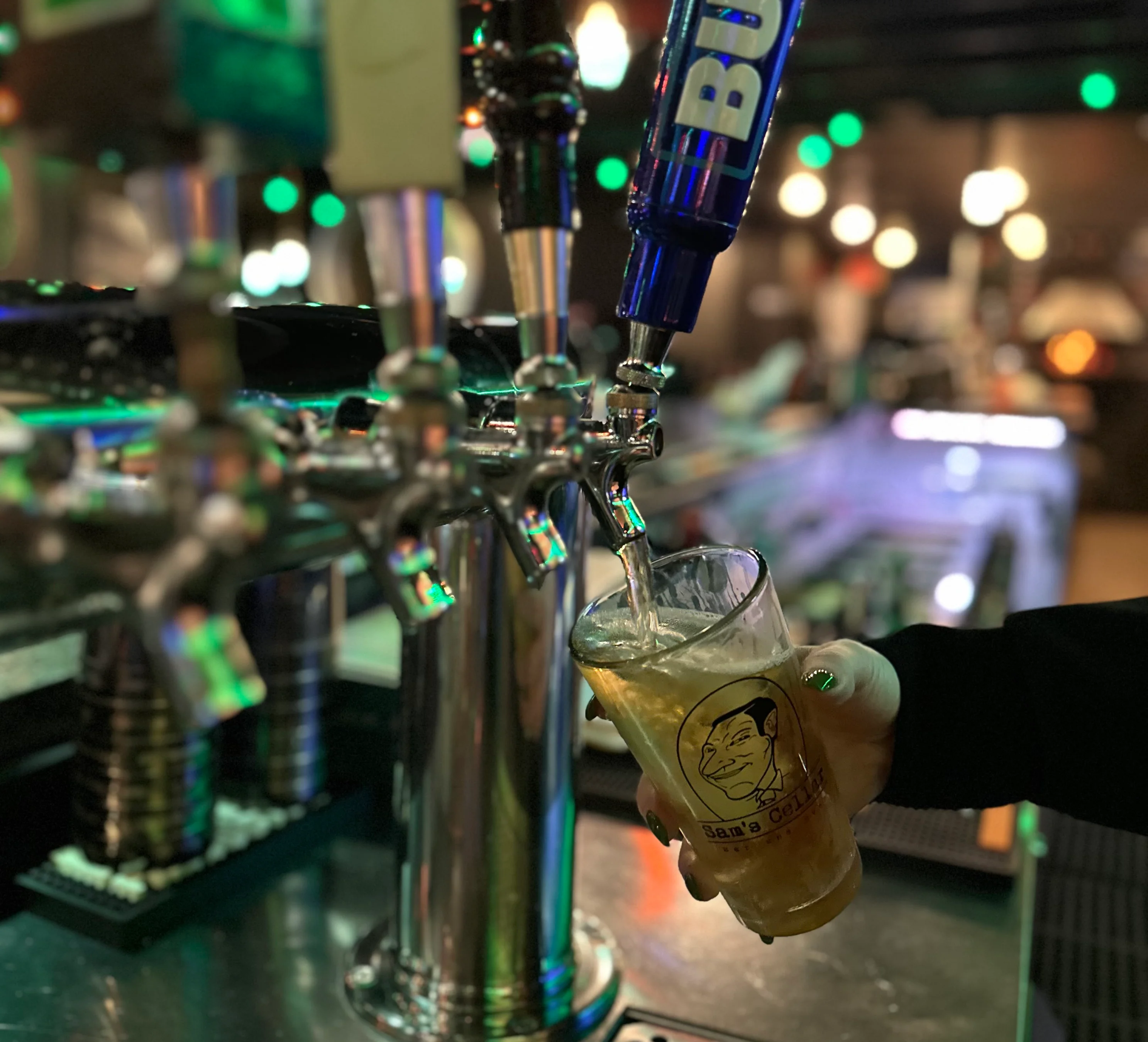 A bartender pouring a beer into a glass with a frothy head.