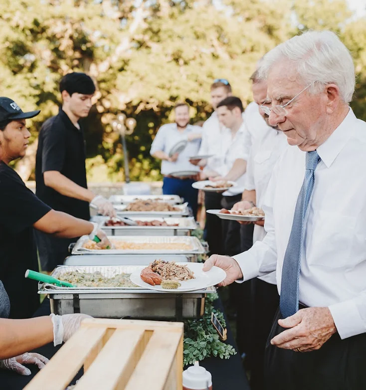 A buffet with food servers and guests