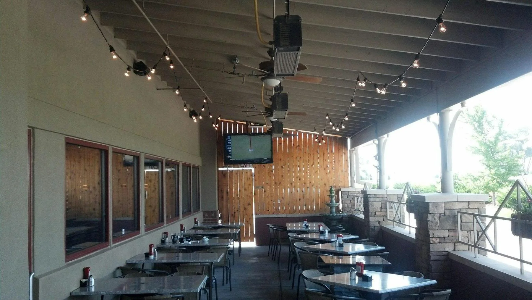 Outdoor dining area with string lights and a TV