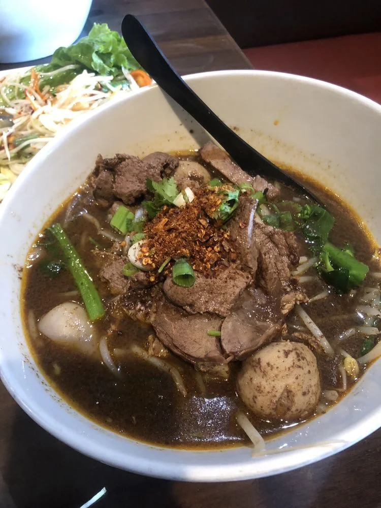 Bowl of Thai boat noodles with beef and herbs