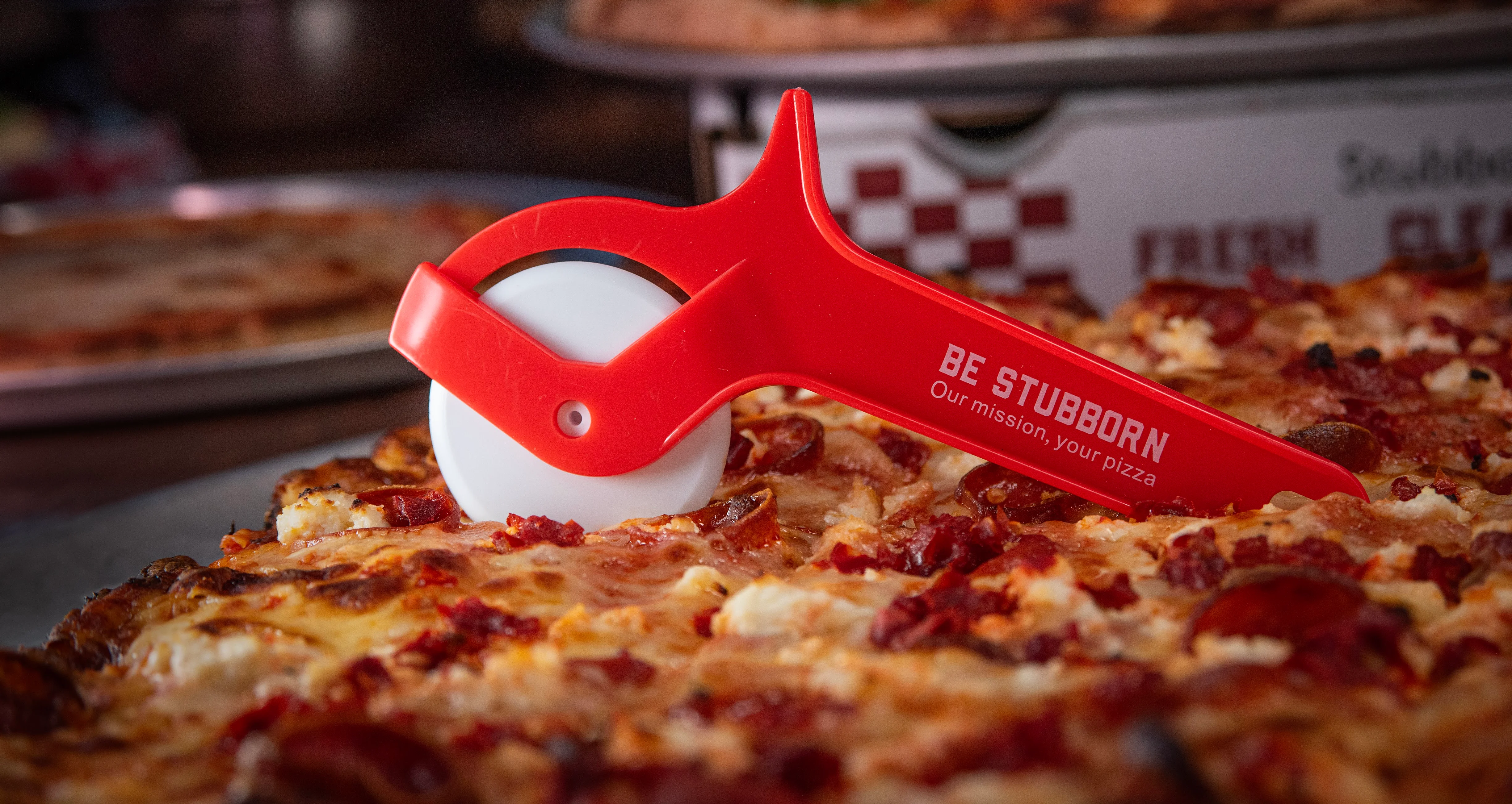 Pizza cutter on a pepperoni pizza in a cozy restaurant setting