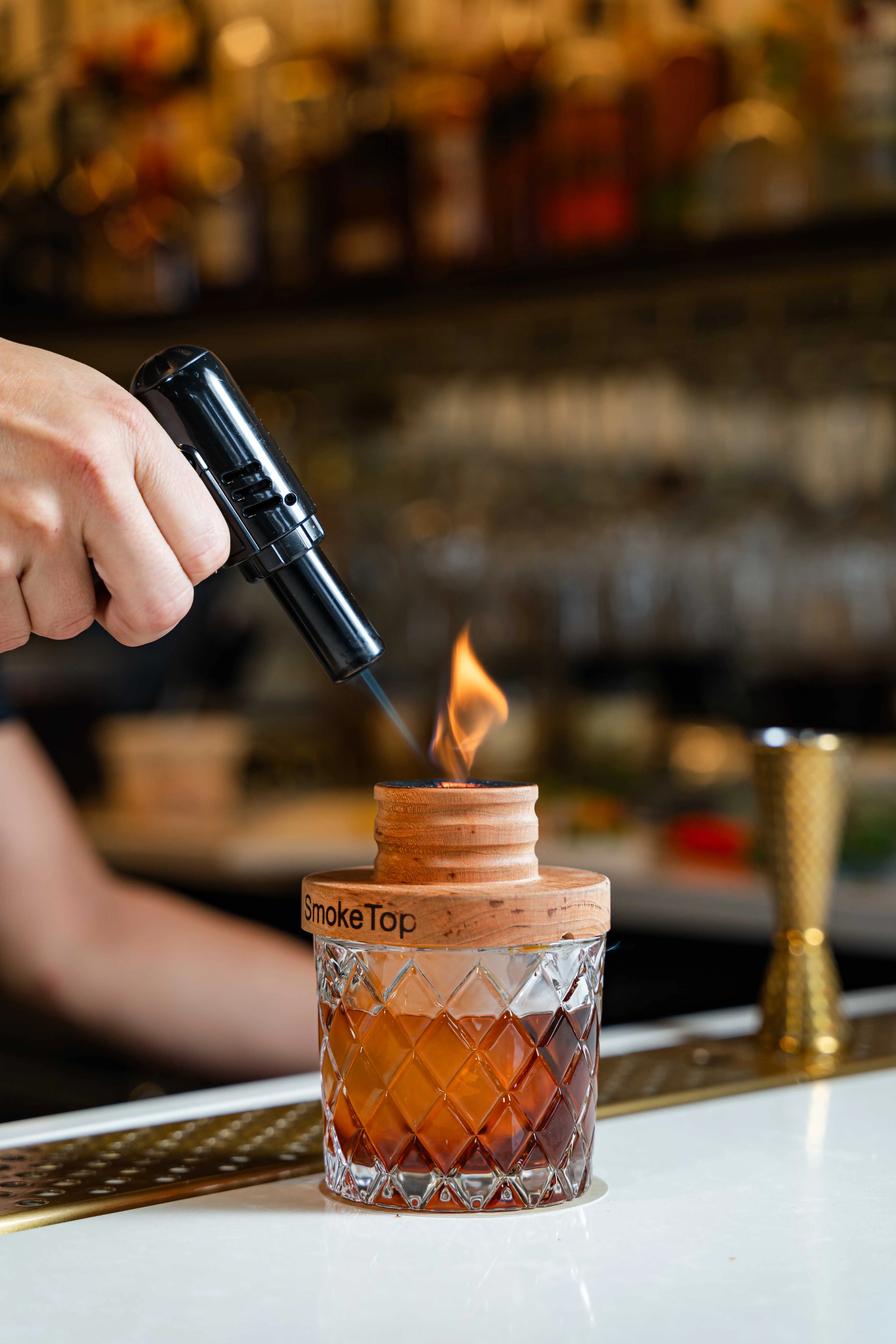 Bartender igniting a cocktail with a SmokeTop device