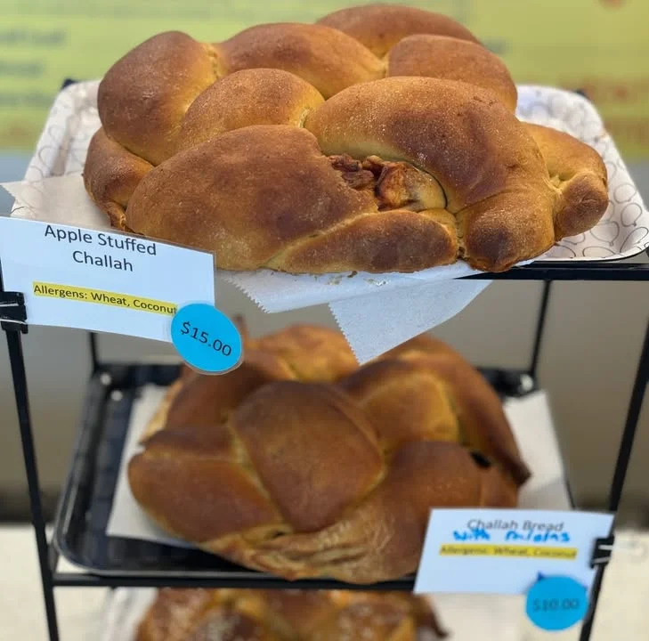 A freshly baked apple stuffed challah bread on display. It's golden brown and fluffy, indicating freshness.