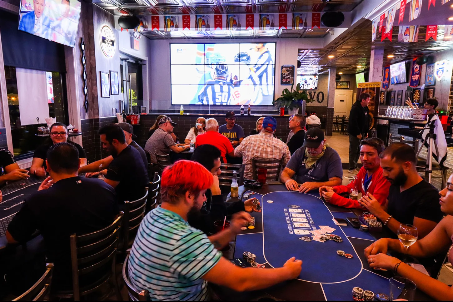 Lively restaurant interior with patrons enjoying poker and sports on large screens