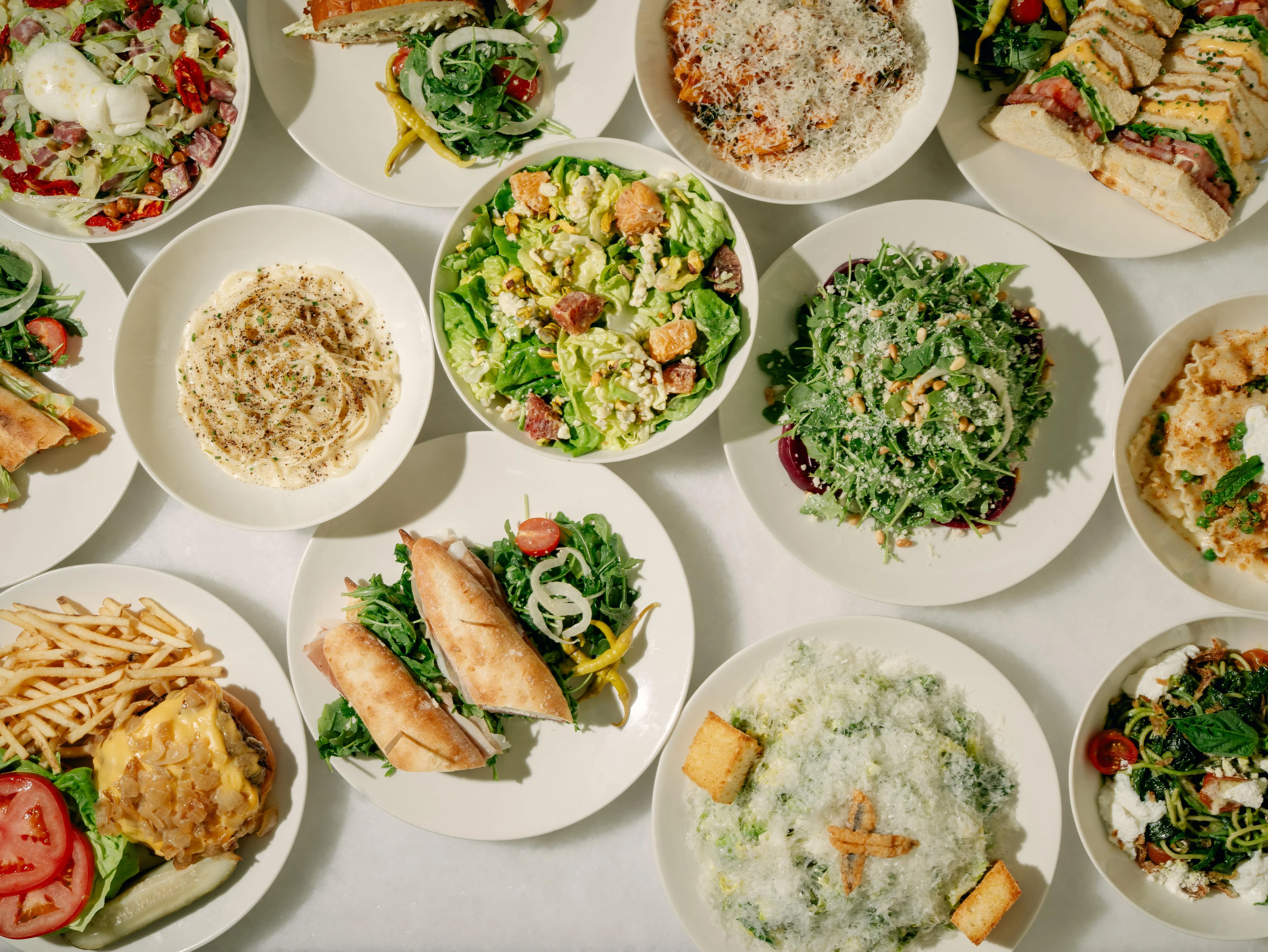 Assorted Italian pasta dishes and salads on white plates