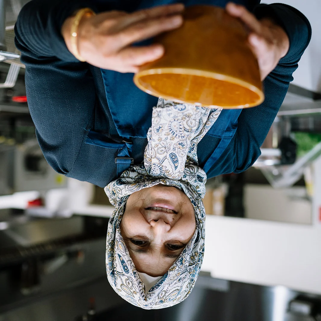 Lead cook at Tripoli’s holding a traditional serving bowl in the restaurant kitchen