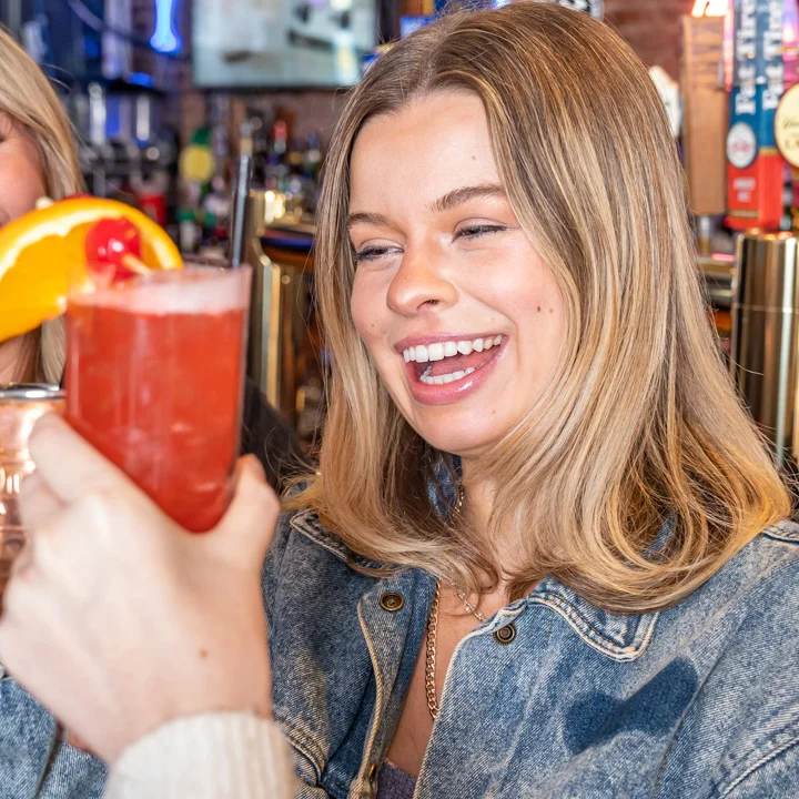 Friends toasting cocktails at a lively bar