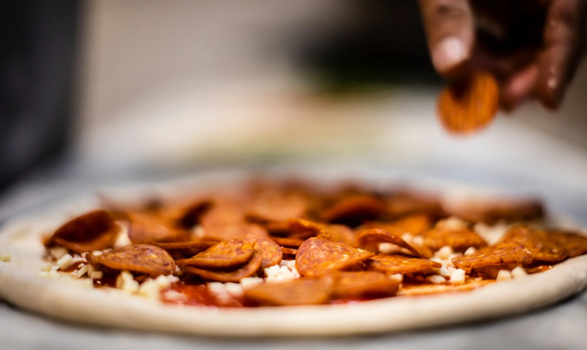 Pepperoni pizza being topped before going into the oven