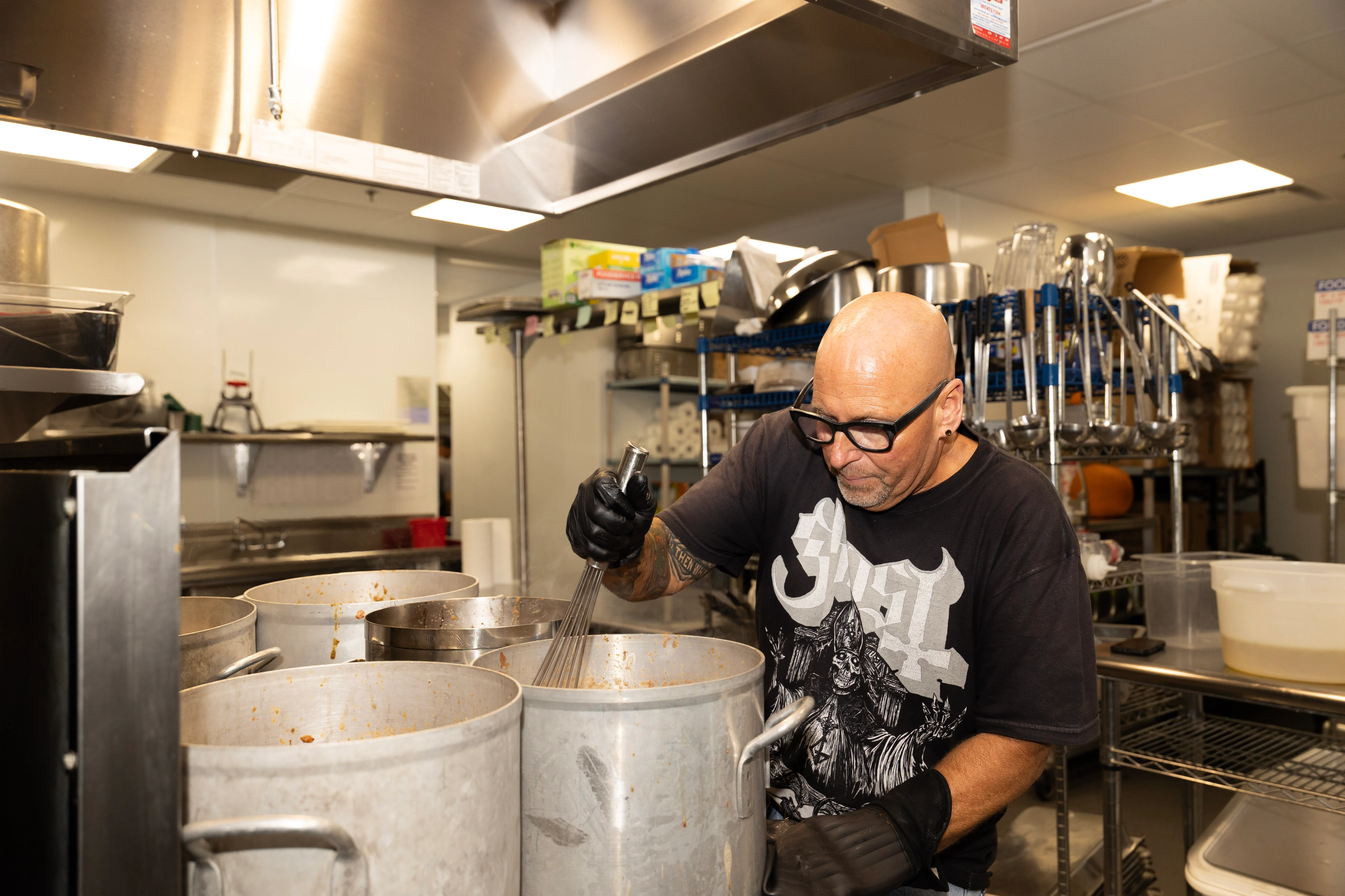 Chef stirring large pots in a professional kitchen