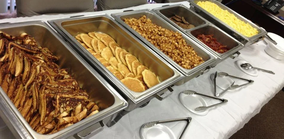 Breakfast buffet with pancakes, bacon, and scrambled eggs