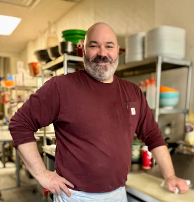 Chef posing in a bustling restaurant kitchen