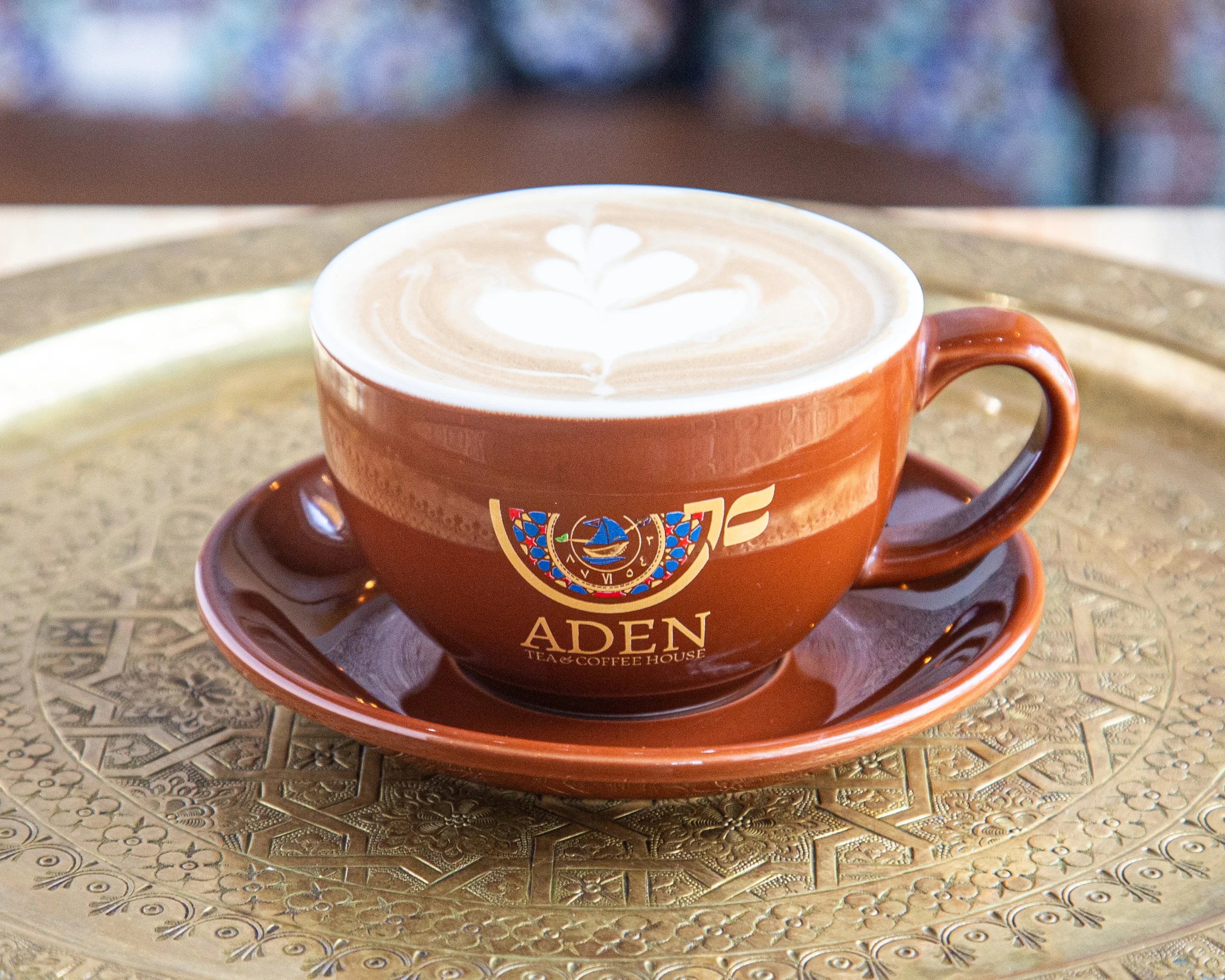 A beautifully crafted latte with intricate foam art in a coffee house setting.