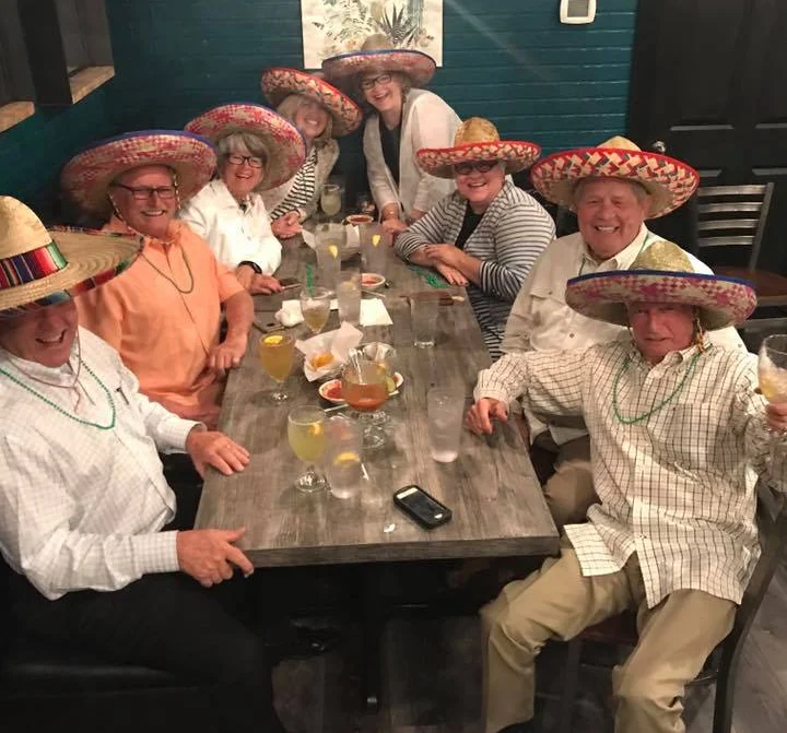 Group of friends celebrating with sombreros in a vibrant restaurant setting