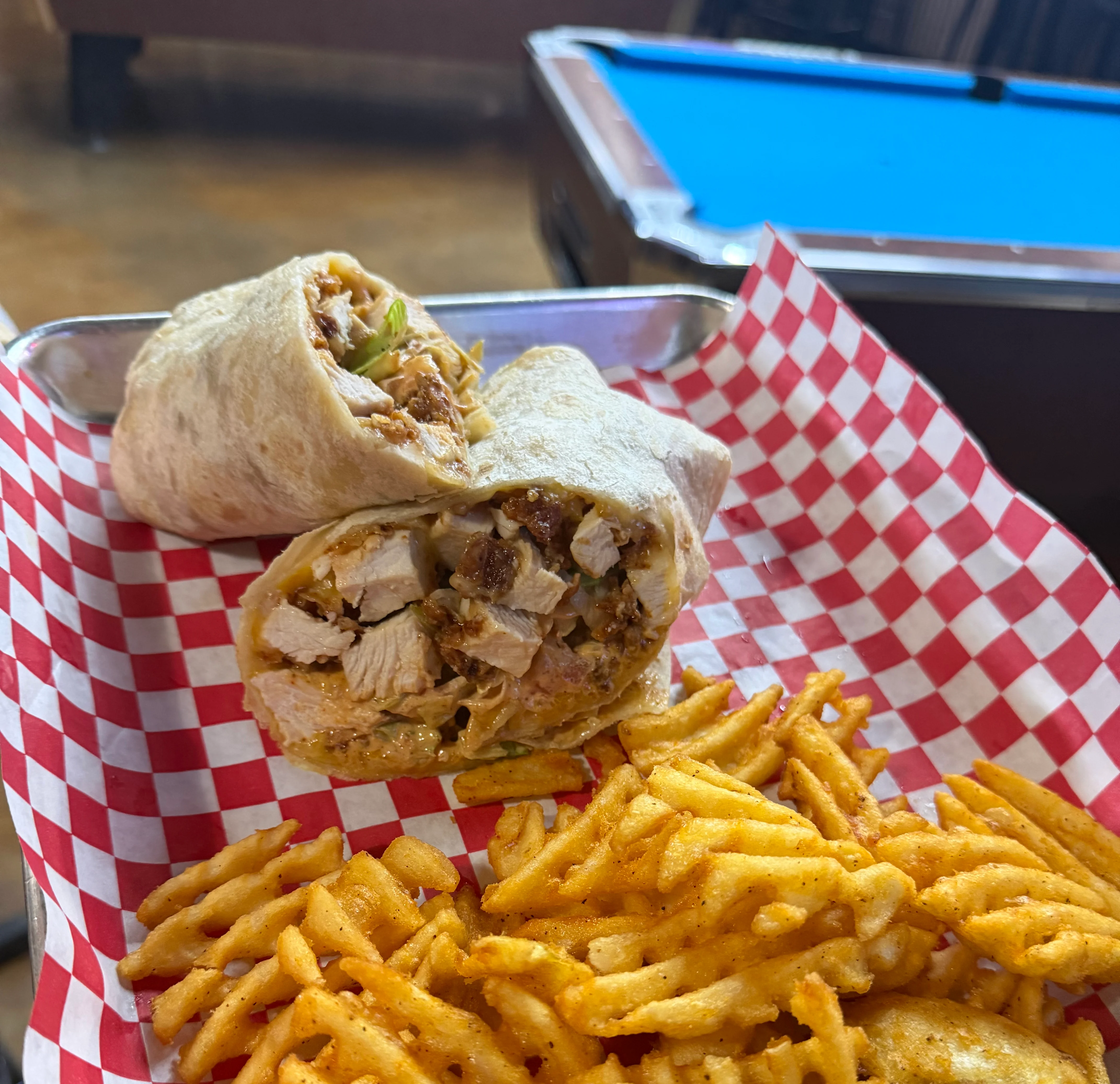 Grilled chicken wrap with waffle fries in a casual dining setting