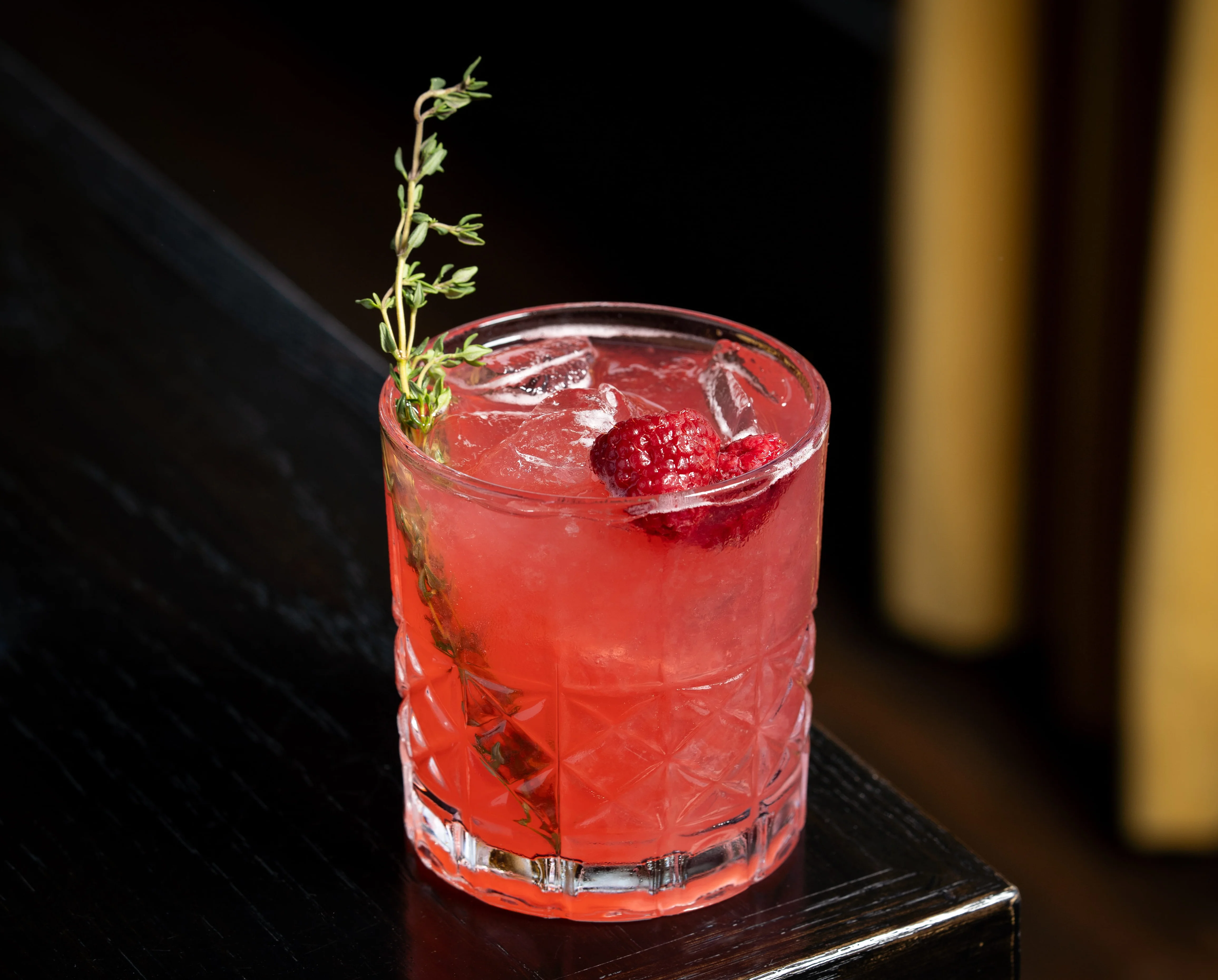 Refreshing cocktail with raspberries and thyme garnish