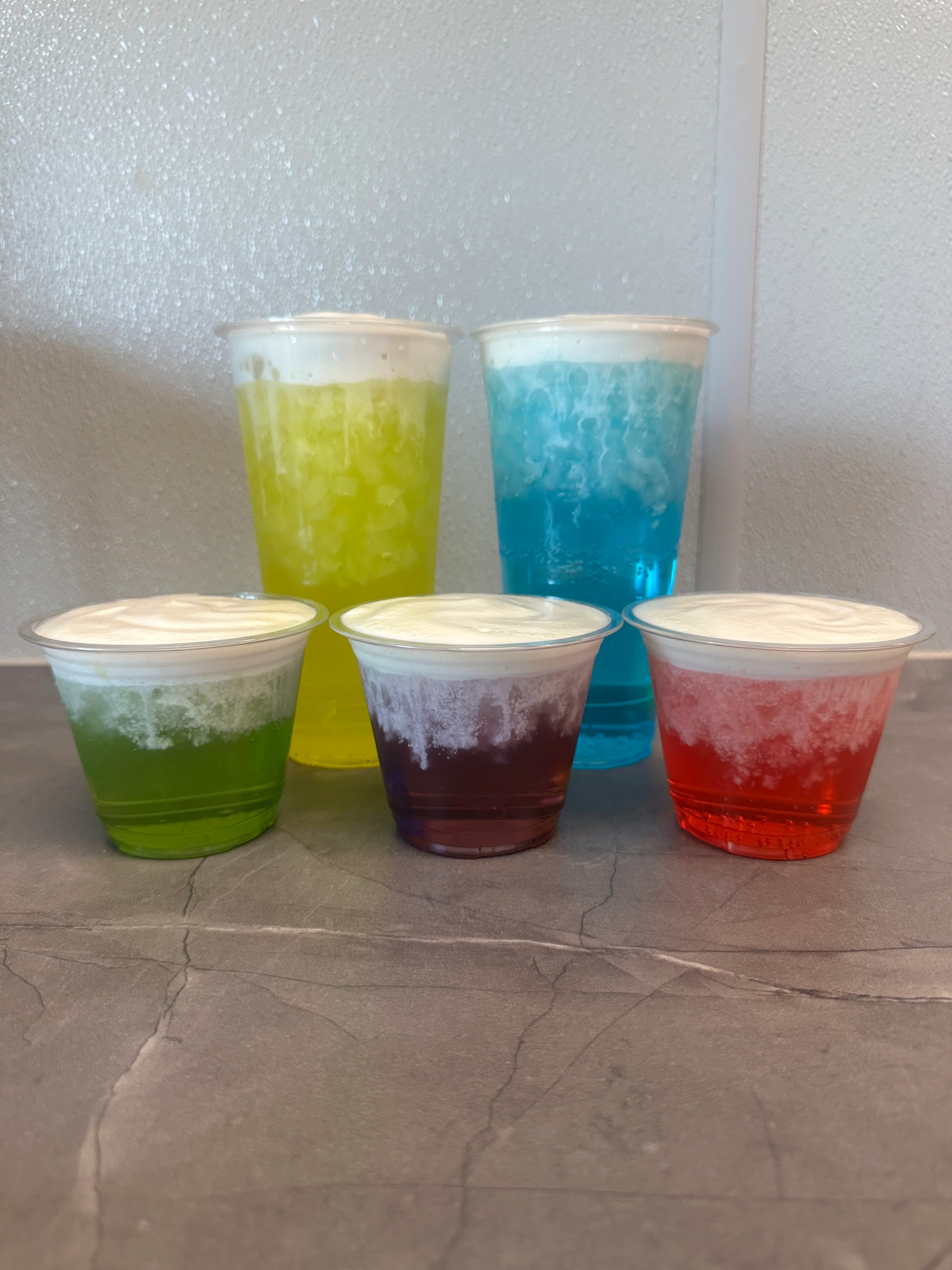 Colorful layered drinks with whipped cream topping