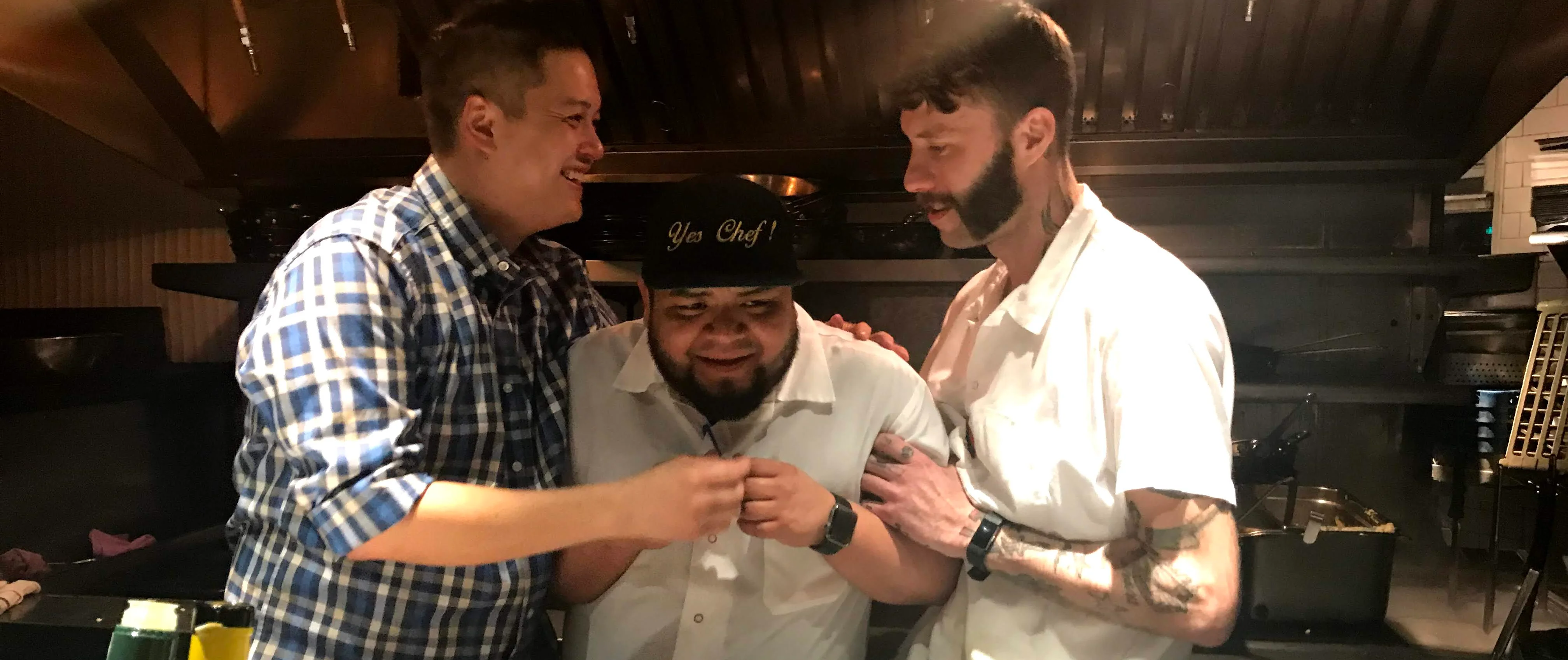 Chefs sharing a light moment in a bustling restaurant kitchen