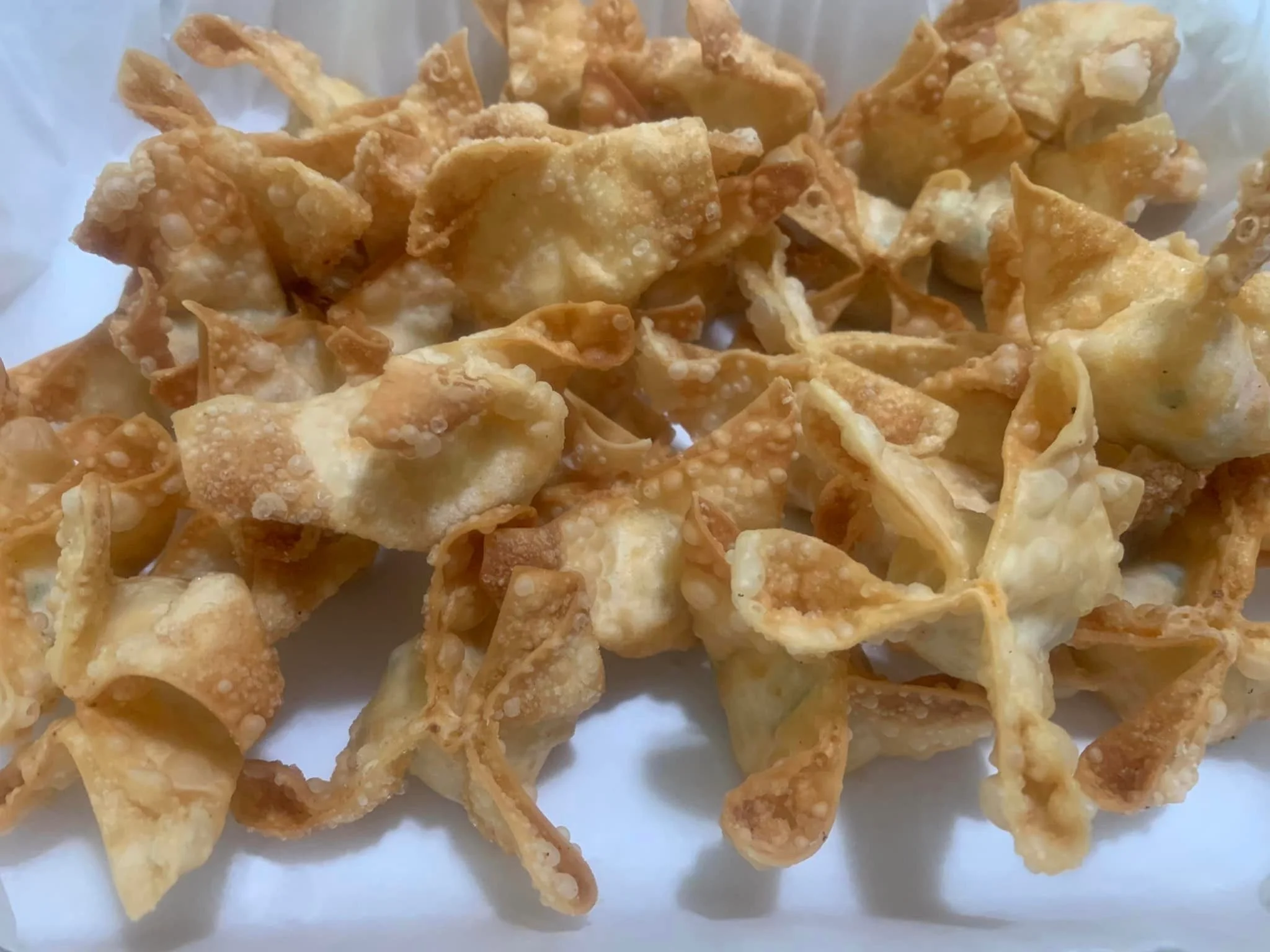 A close-up of crispy, golden fried wonton wrappers piled together.