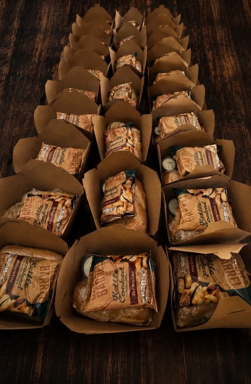 Multiple takeout boxes filled with snacks arranged neatly on a wooden surface.