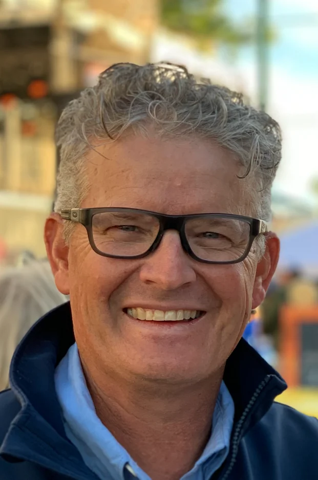 Smiling man in casual attire at an outdoor event