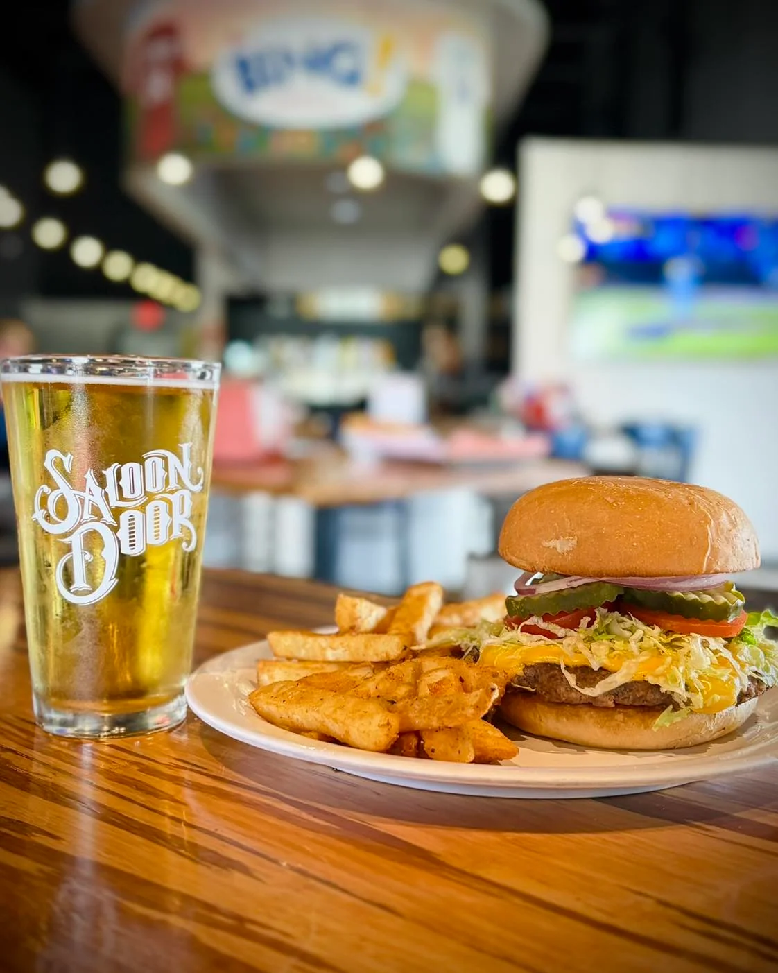 A delicious burger with fries and a cold beer on a wooden table.