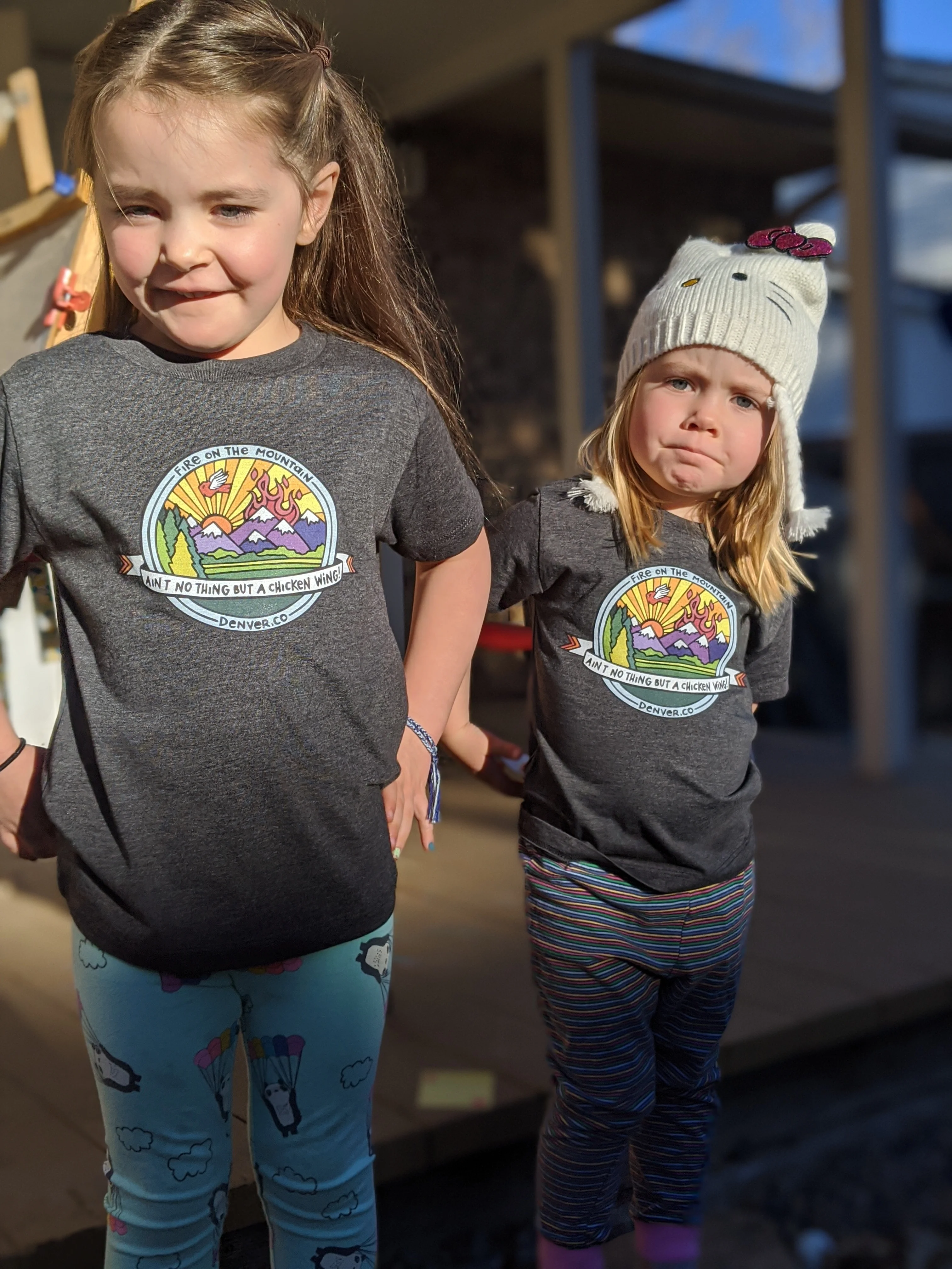 Two children wearing matching graphic t-shirts outdoors