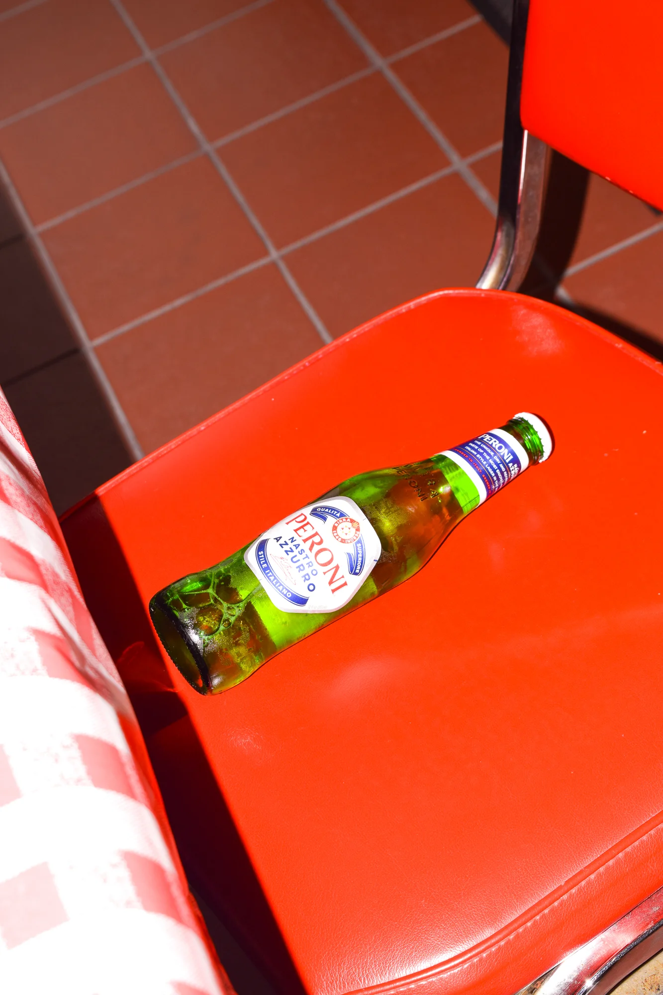 Chilled Peroni beer bottle on a vibrant red chair