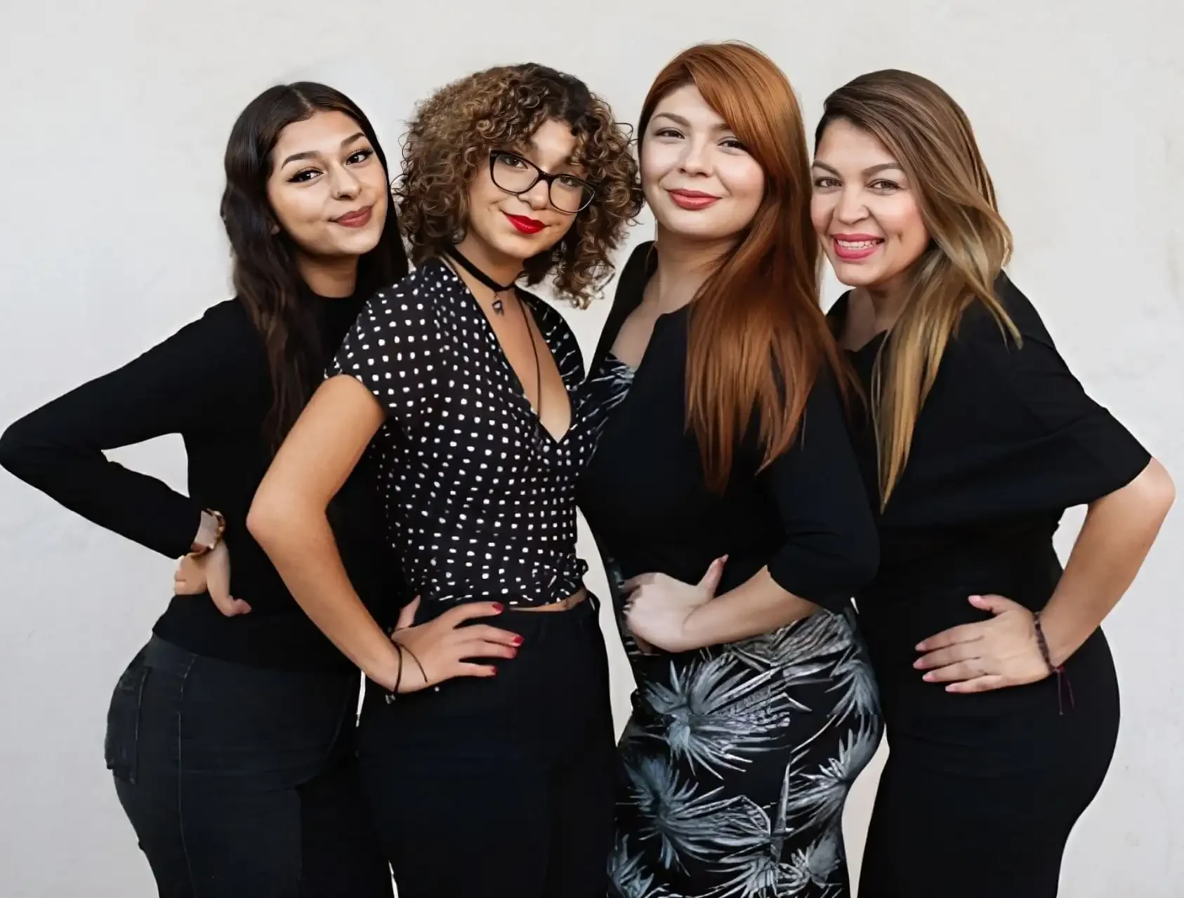 Group of four women posing together in stylish outfits