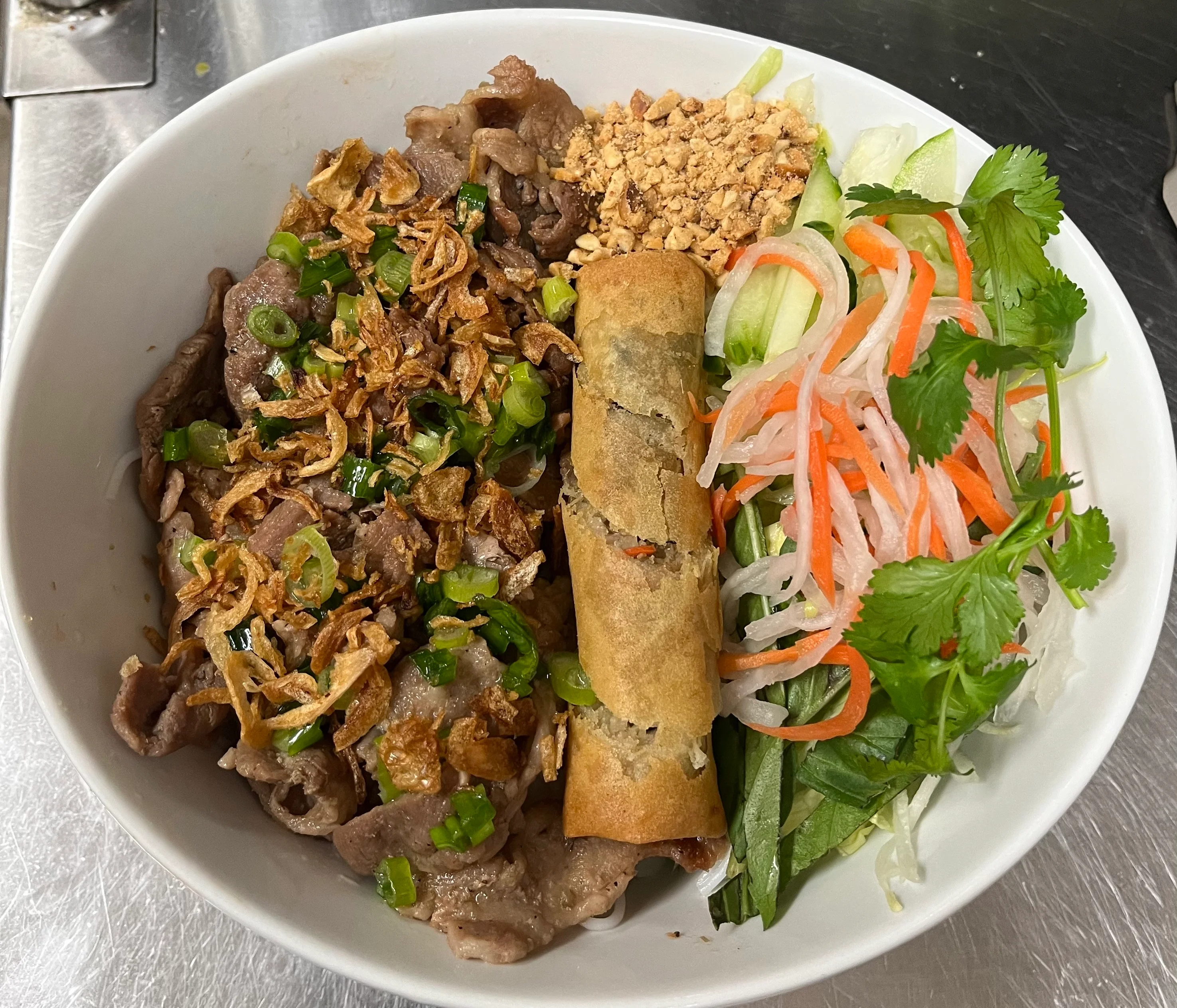 Vietnamese bun thit nuong with spring rolls and fresh herbs