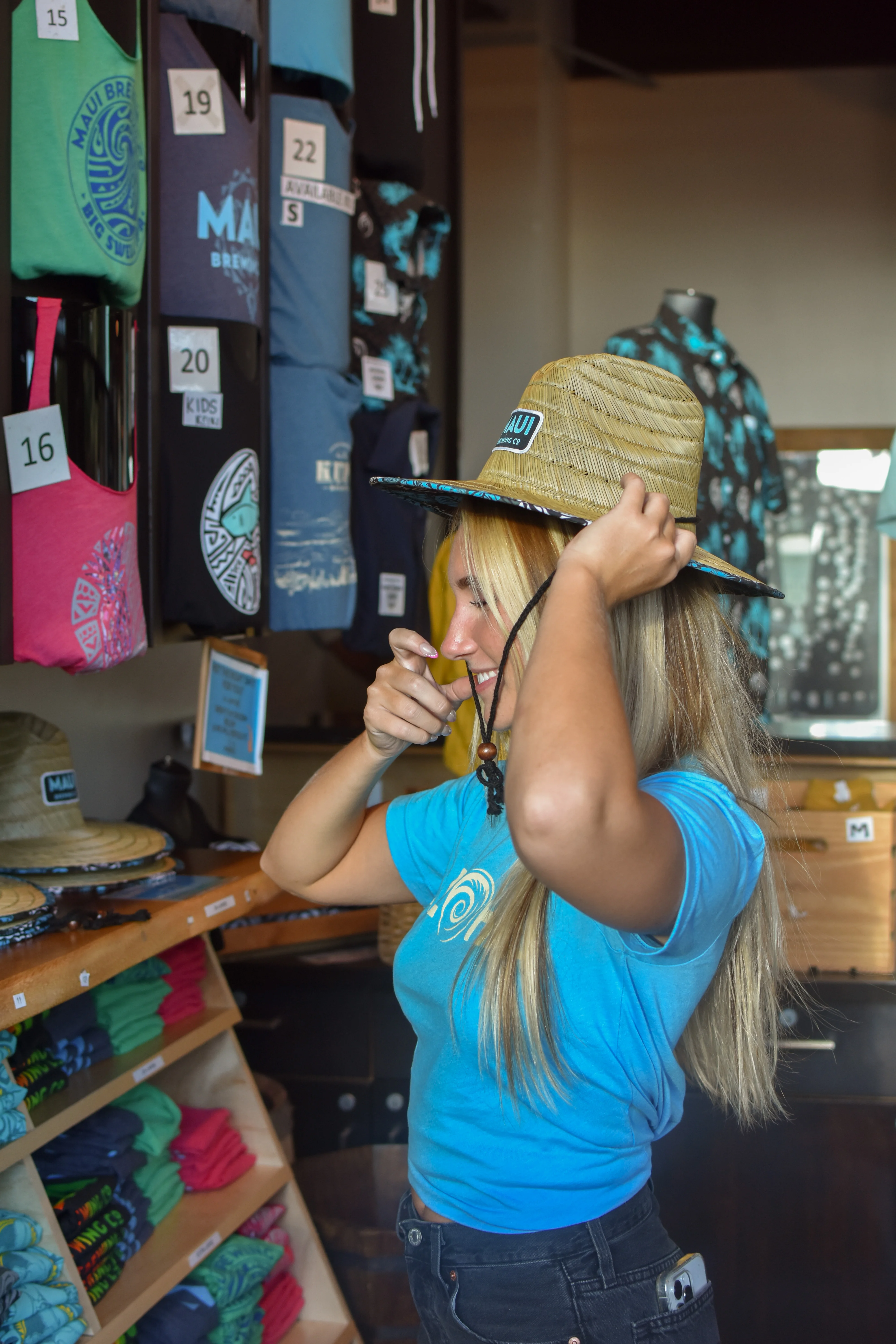 Customer trying on a straw hat in a vibrant retail store
