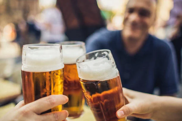 Cheers with three glasses of beer in a lively outdoor setting