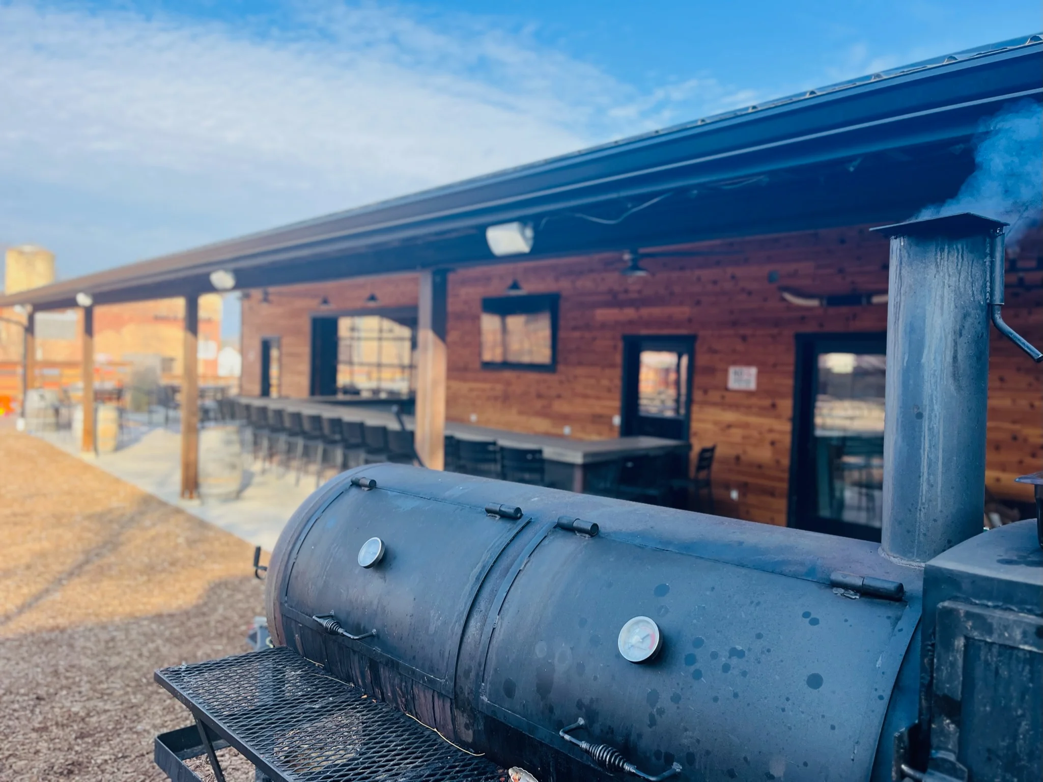 Outdoor barbecue area with a smoker and rustic wooden building