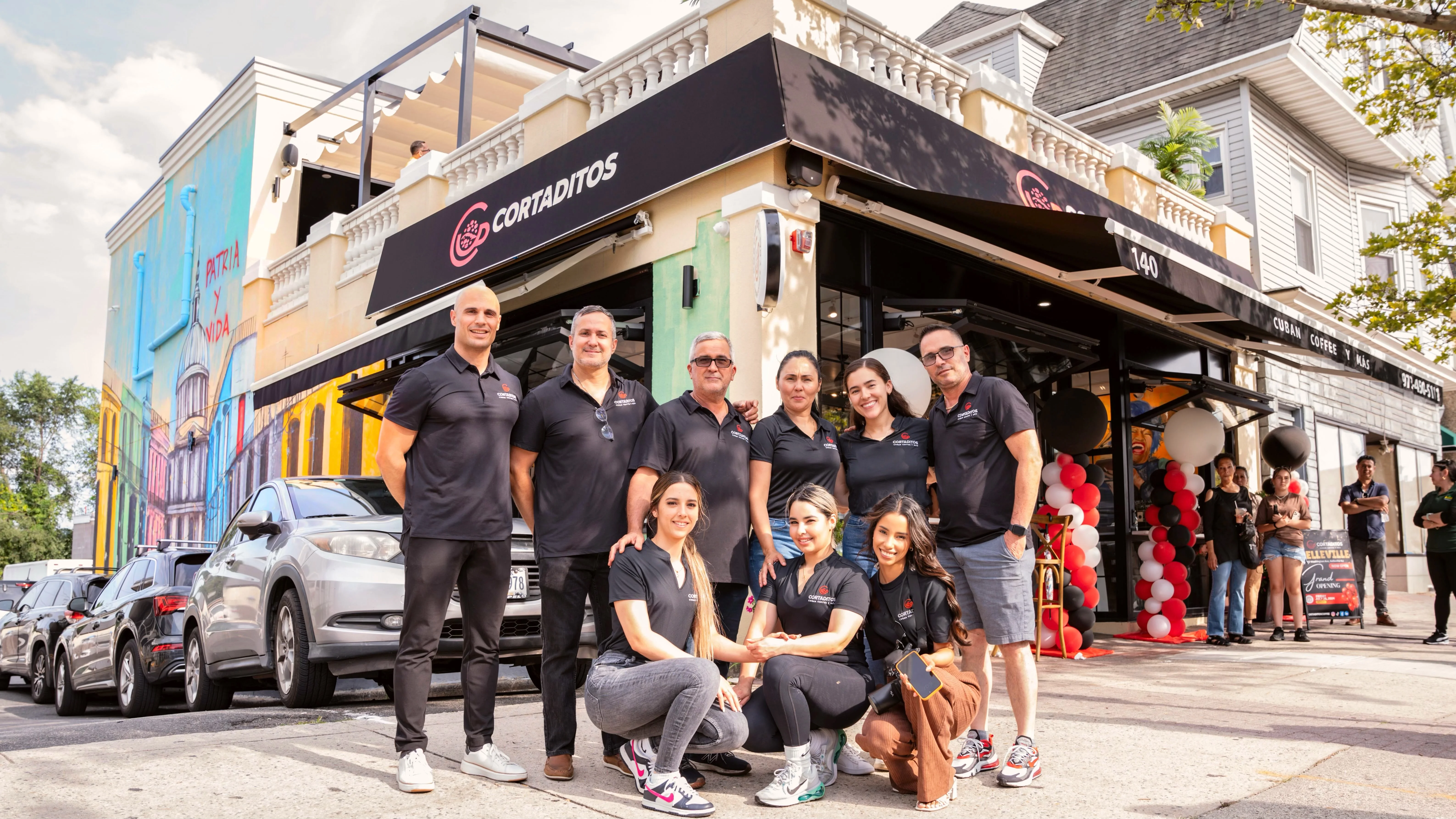 Cuban coffee shop team in front of vibrant mural