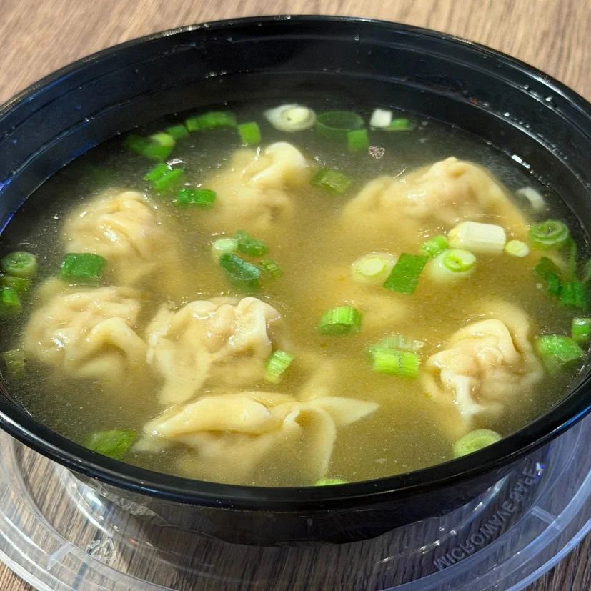 Bowl of dumplings in broth garnished with green onions.