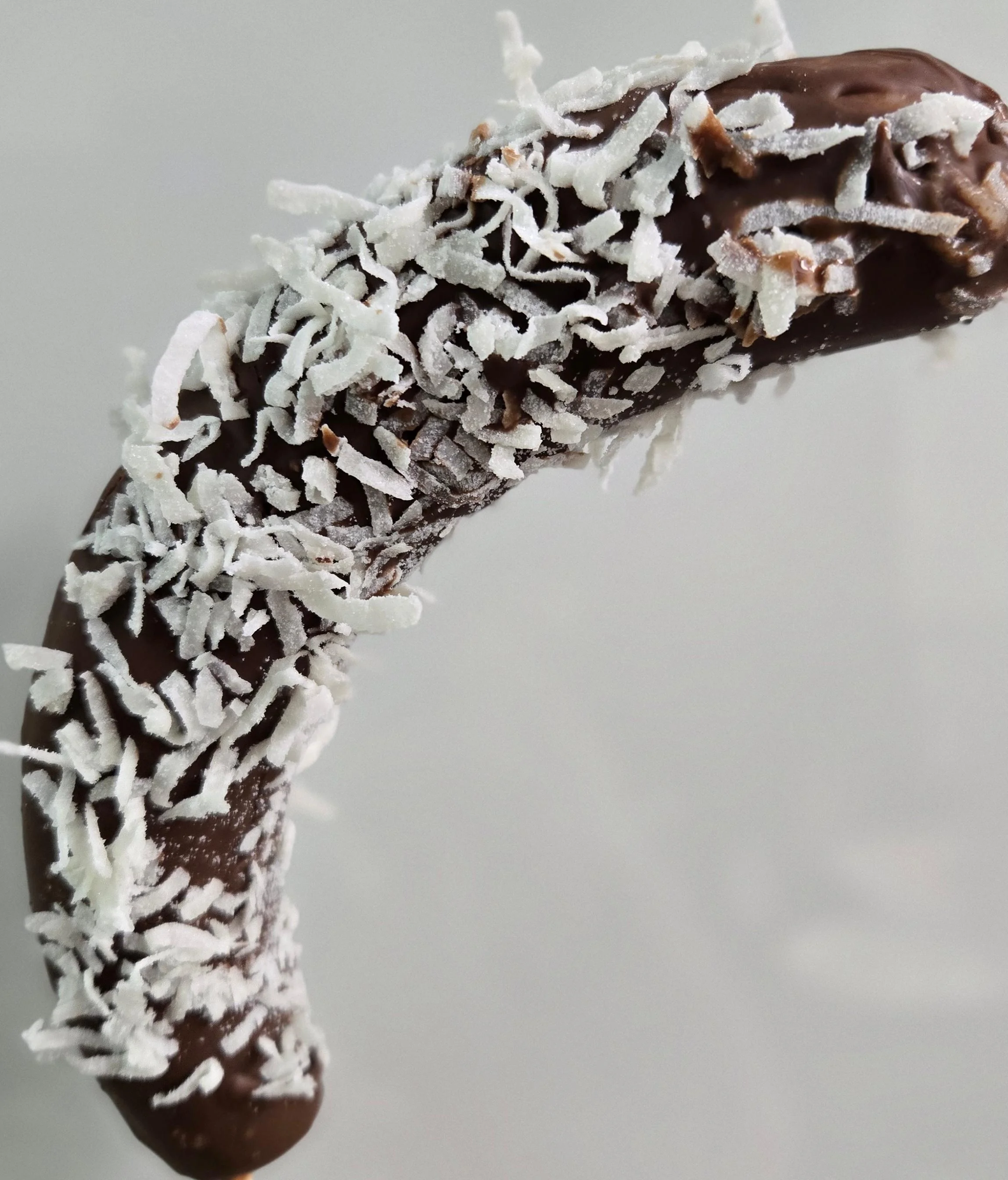 A chocolate-covered banana roll, coated with shredded coconut, showcasing its unique texture.