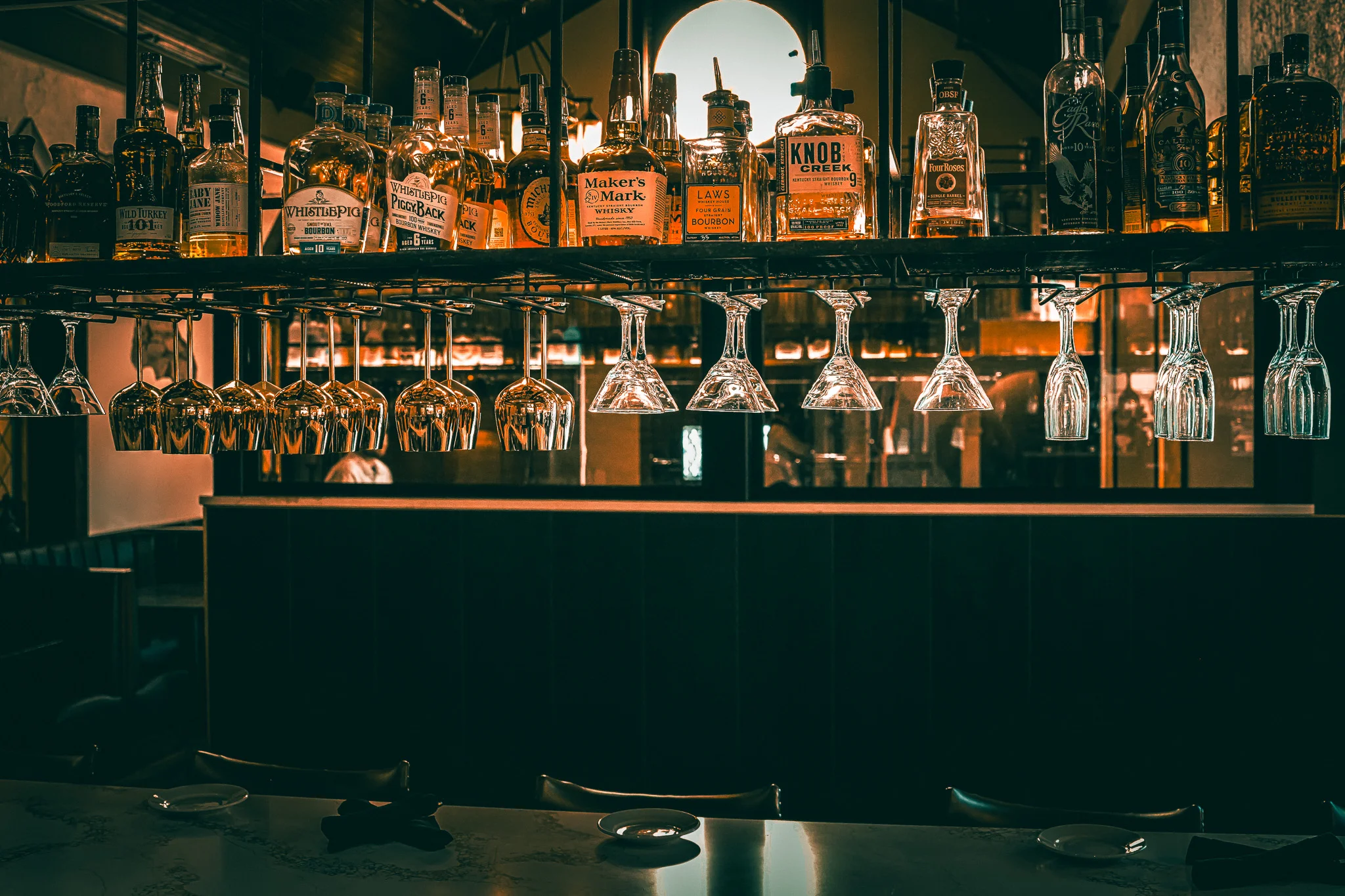 Upscale bourbon bar with whiskey bottles and hanging wine glasses