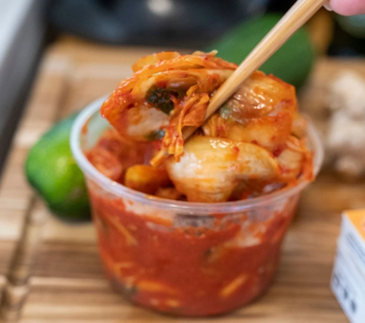 Korean kimchi in a plastic container with chopsticks