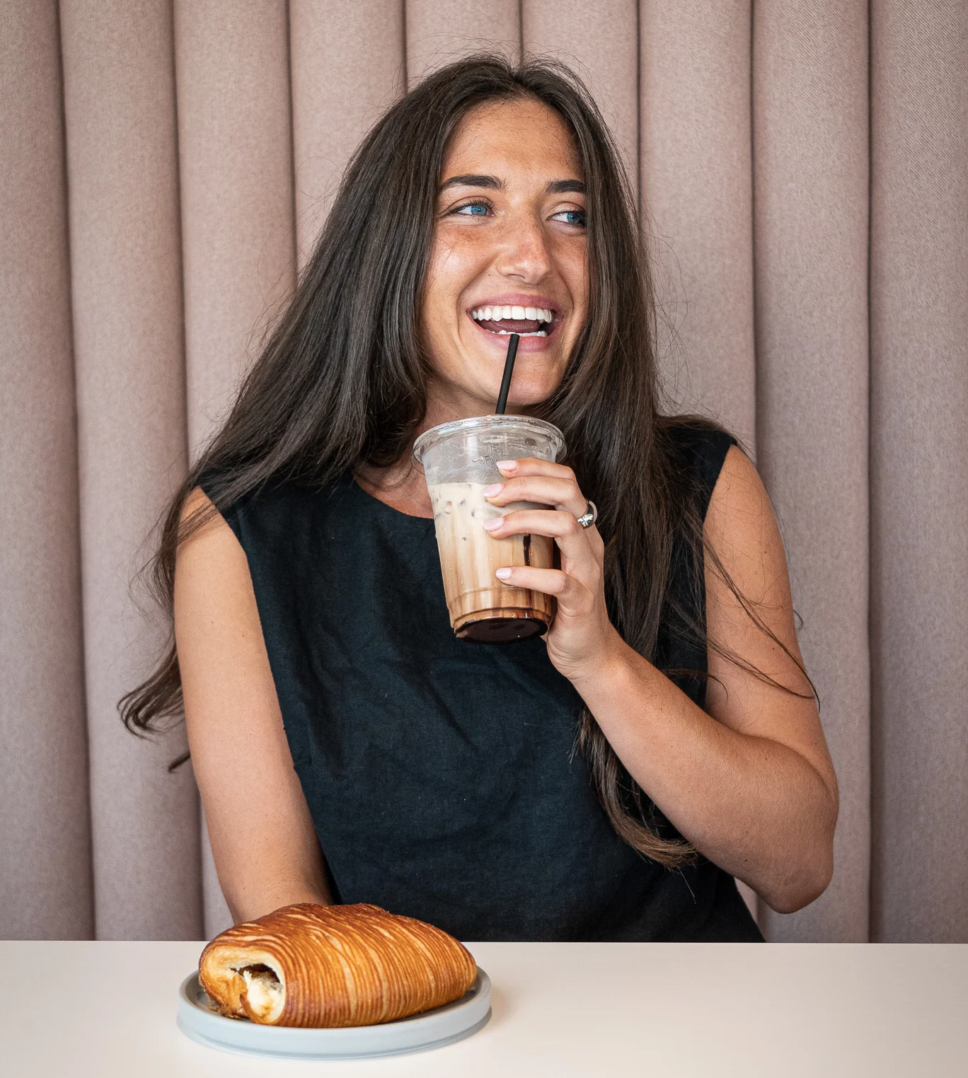 Woman enjoying a croissant and iced coffee in a cozy café