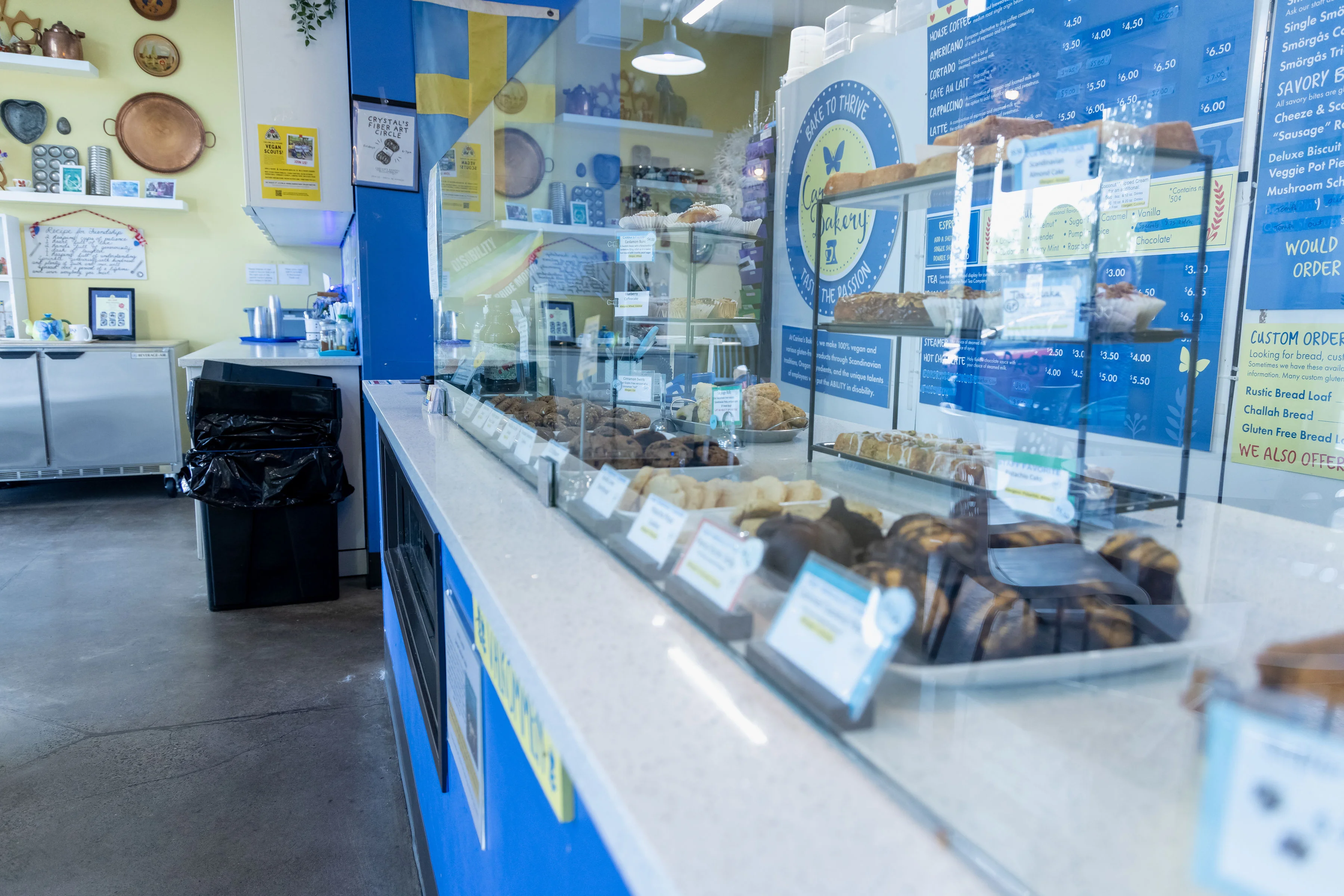A promotional image of a bakery owner smiling in front of her business, showcasing the vegan cafe along with various baked goods.