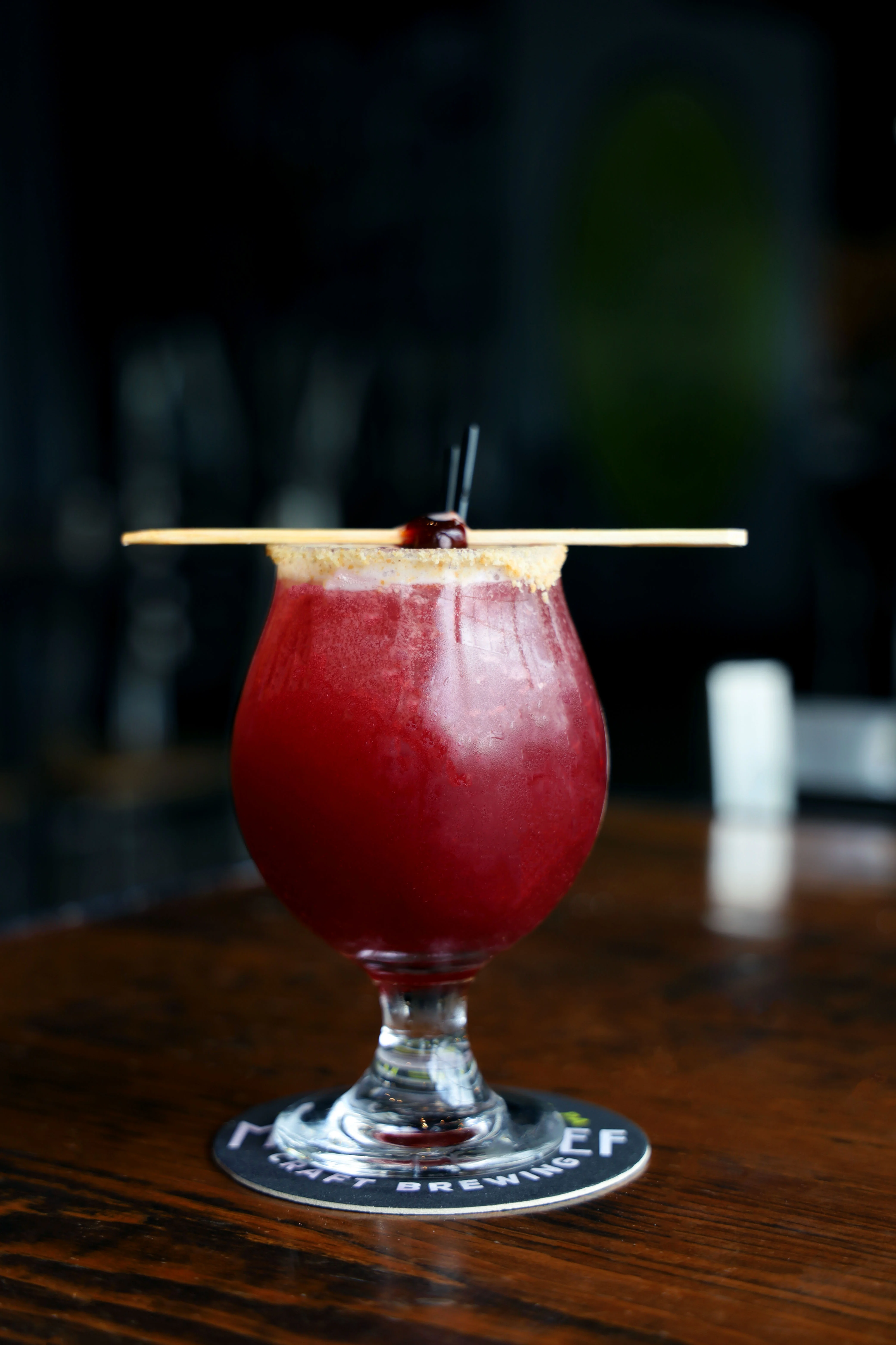 A refreshing Hibiscus Hop Water in a clear glass with a vibrant color.