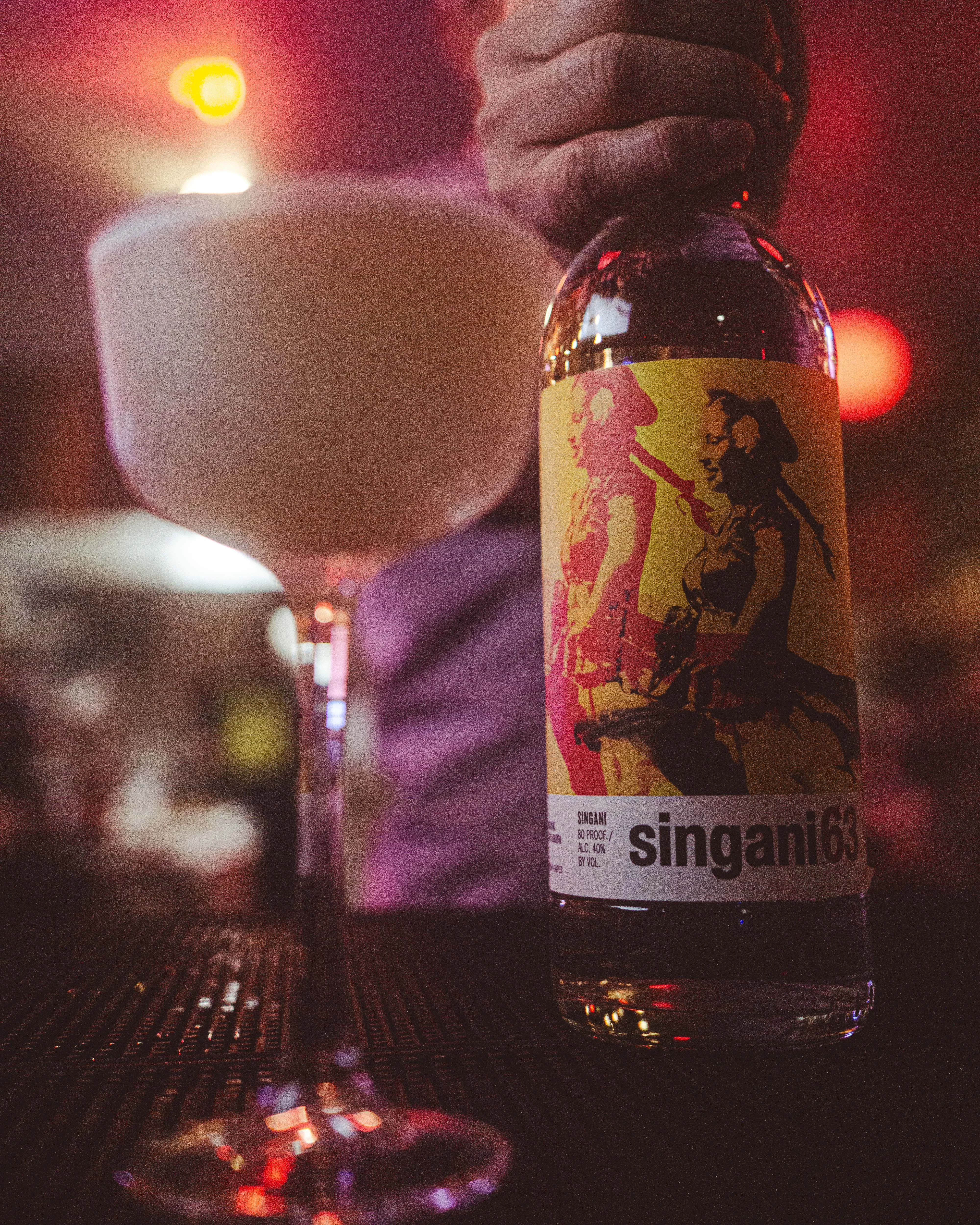 Bartender pouring Singani 63 cocktail at a vibrant bar